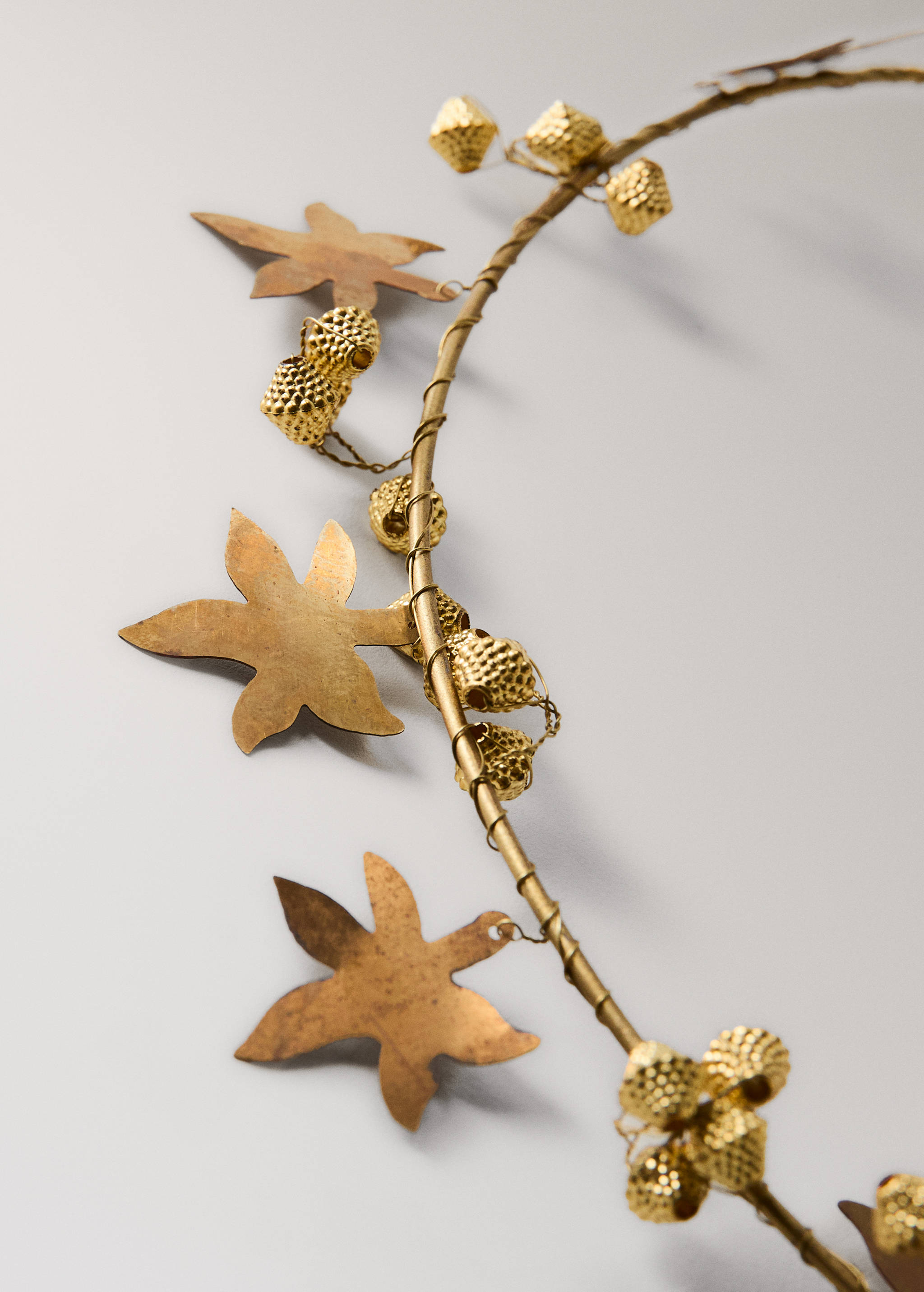 Close-up of a gold metallic decorative garland with leaf and berry details.