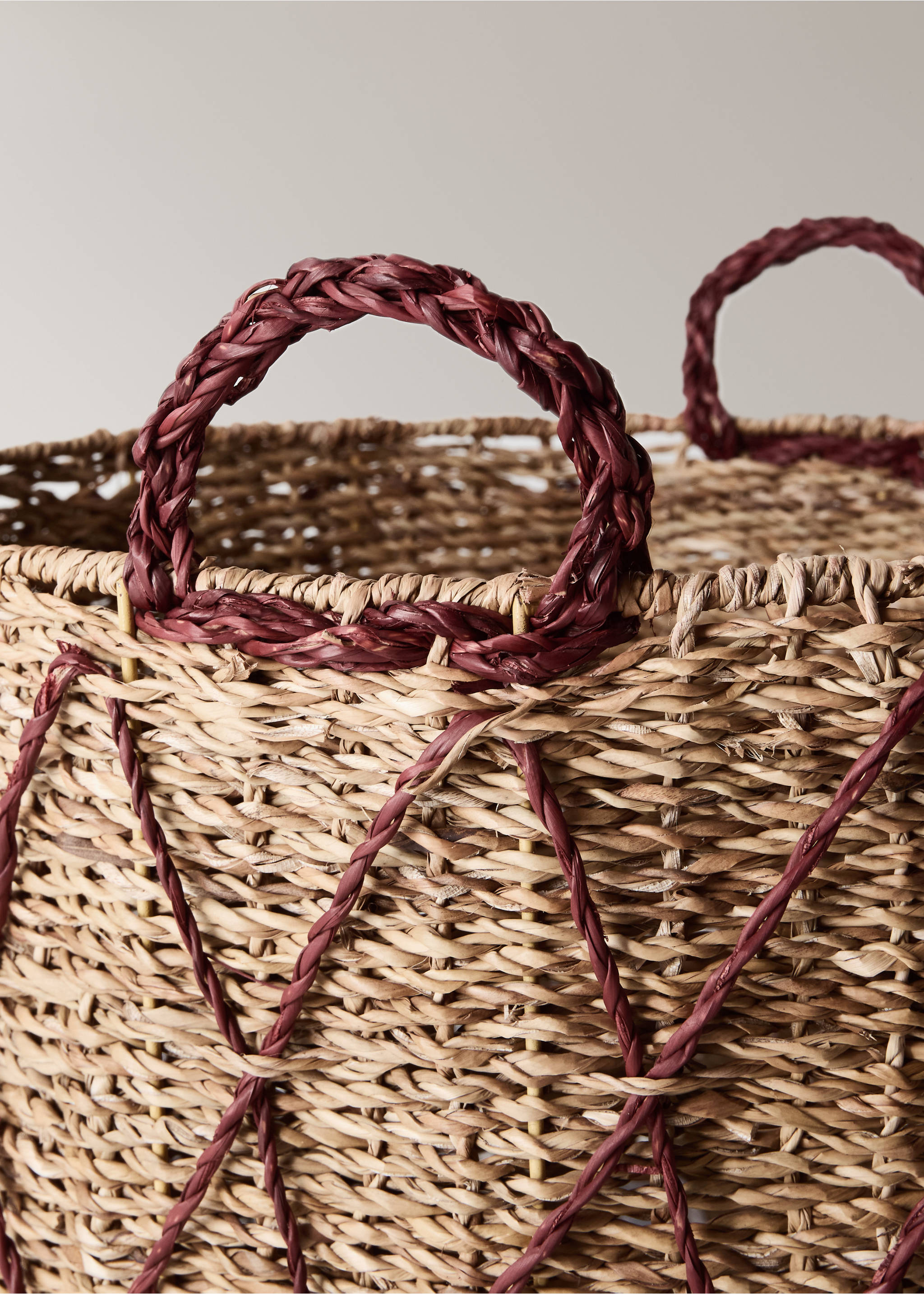 Close-up of a woven natural basket with braided red handles., Brown. Ref: 37066736-00.