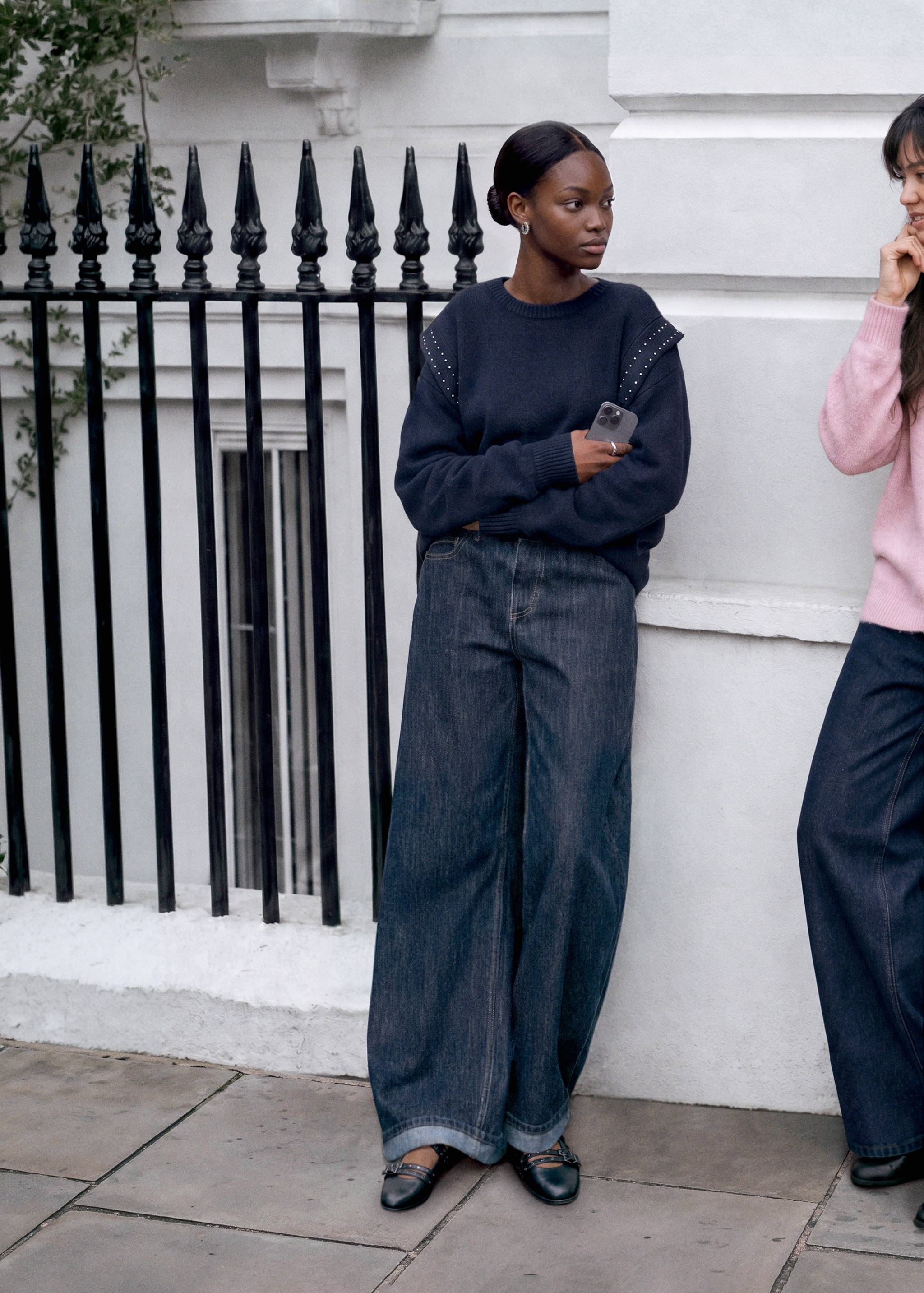 Dark blue knitted jersey with studded shoulders worn with wide-leg denim trousers.
