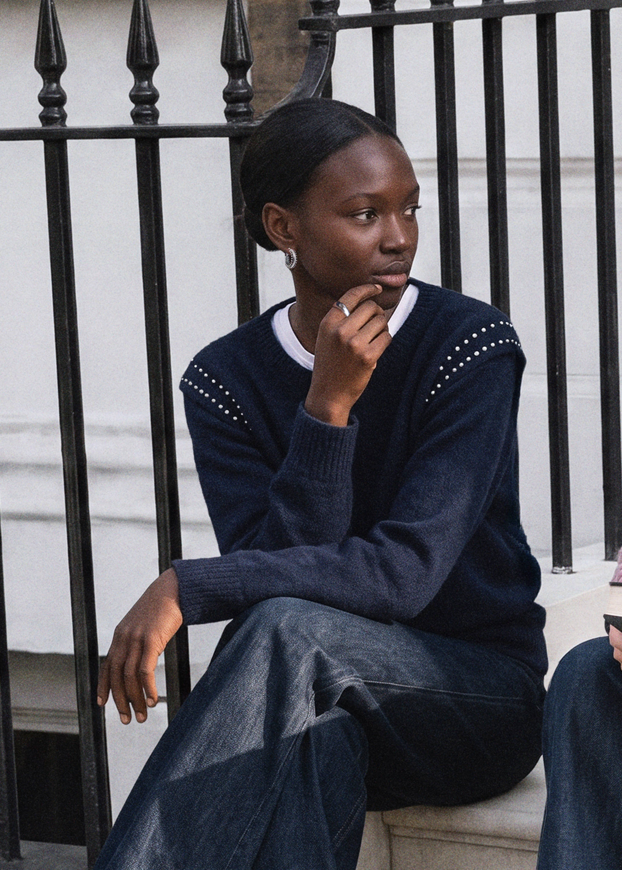 Navy blue knit jersey with studded shoulders worn over a white tee.