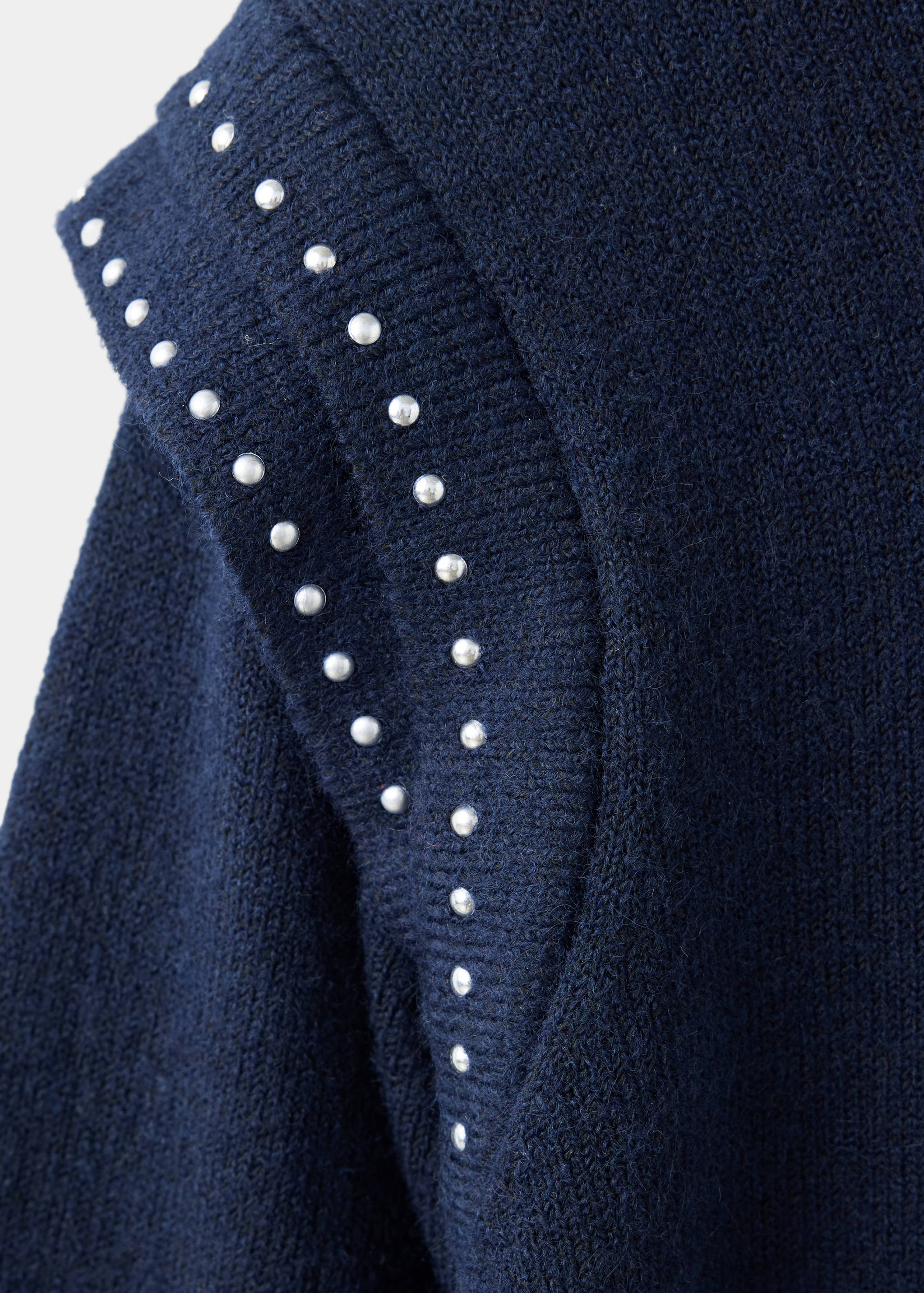Close-up of a dark blue jersey with silver stud details on the shoulder seam.
