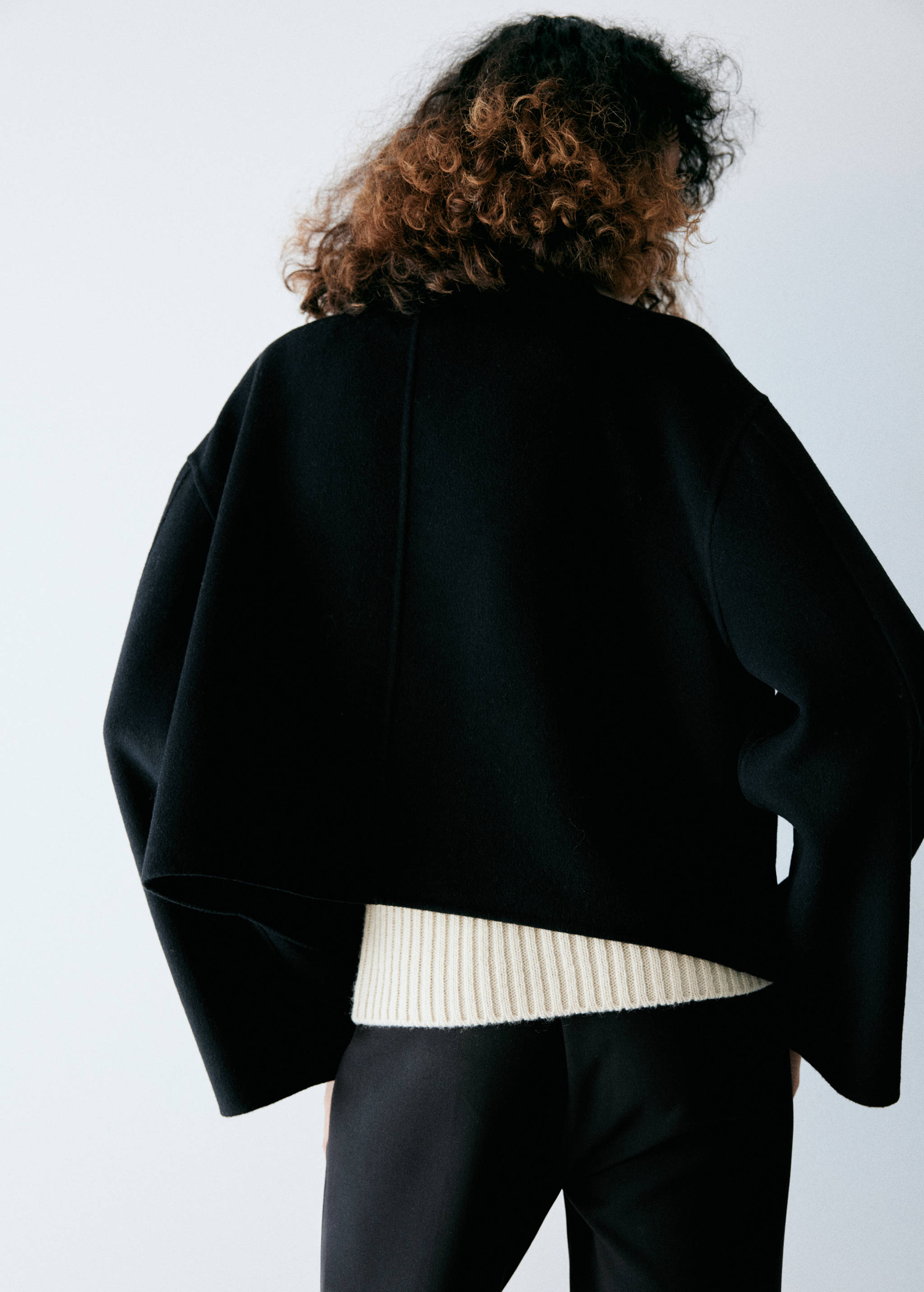 Black cropped jacket with wide sleeves, back view.