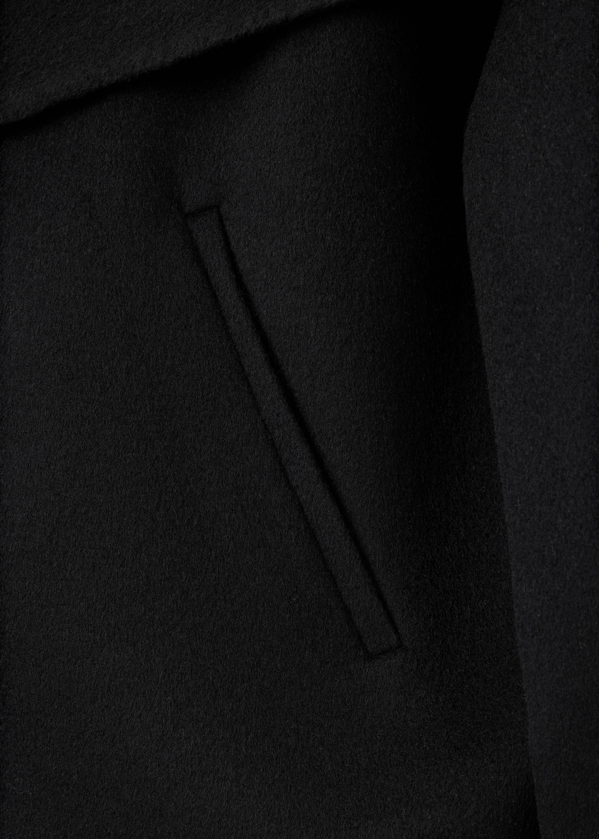 Close-up of the fabric and pocket detail of a black jacket.