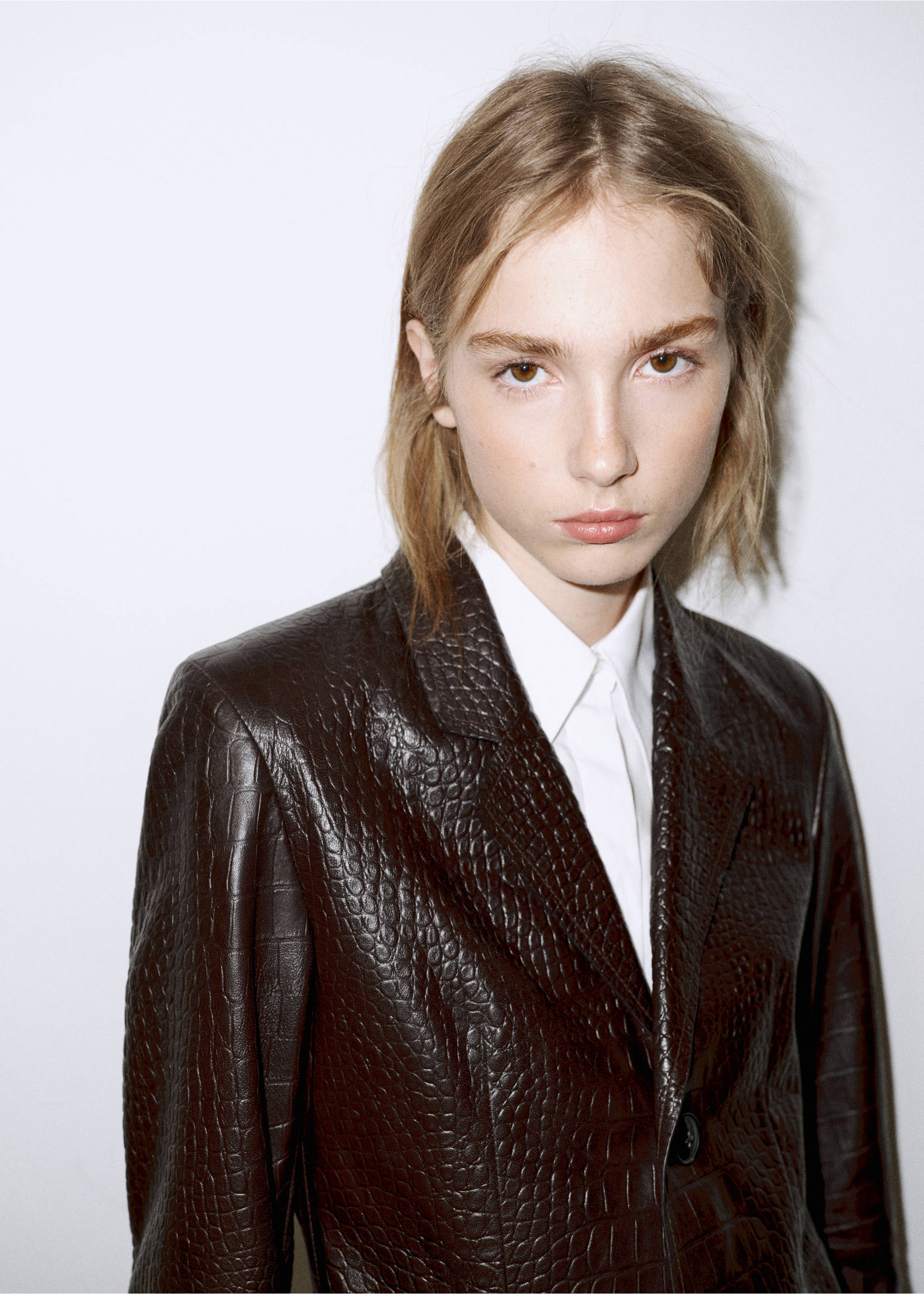 Close-up of a dark brown crocodile-embossed coat with lapels and a white shirt., Brown. Ref: 37067773-01.