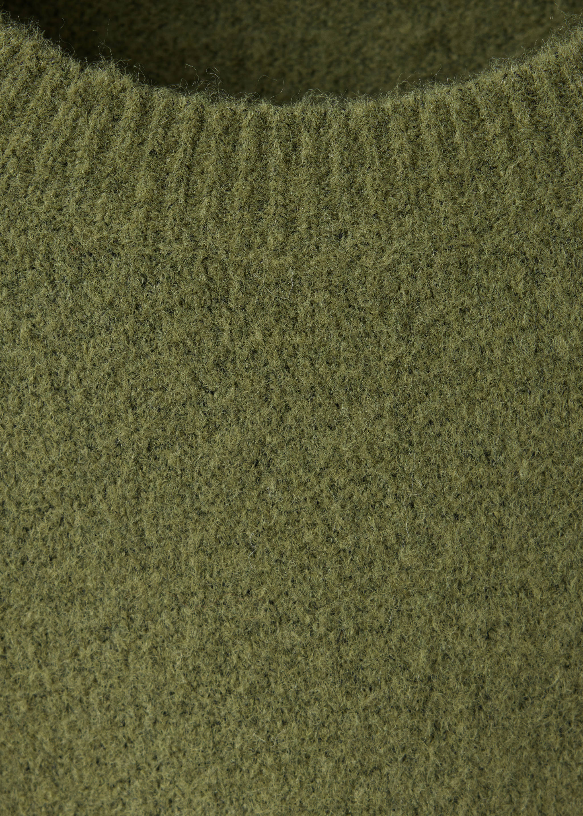 Olive green knitted dress detail showing textured fabric and ribbed crew neck