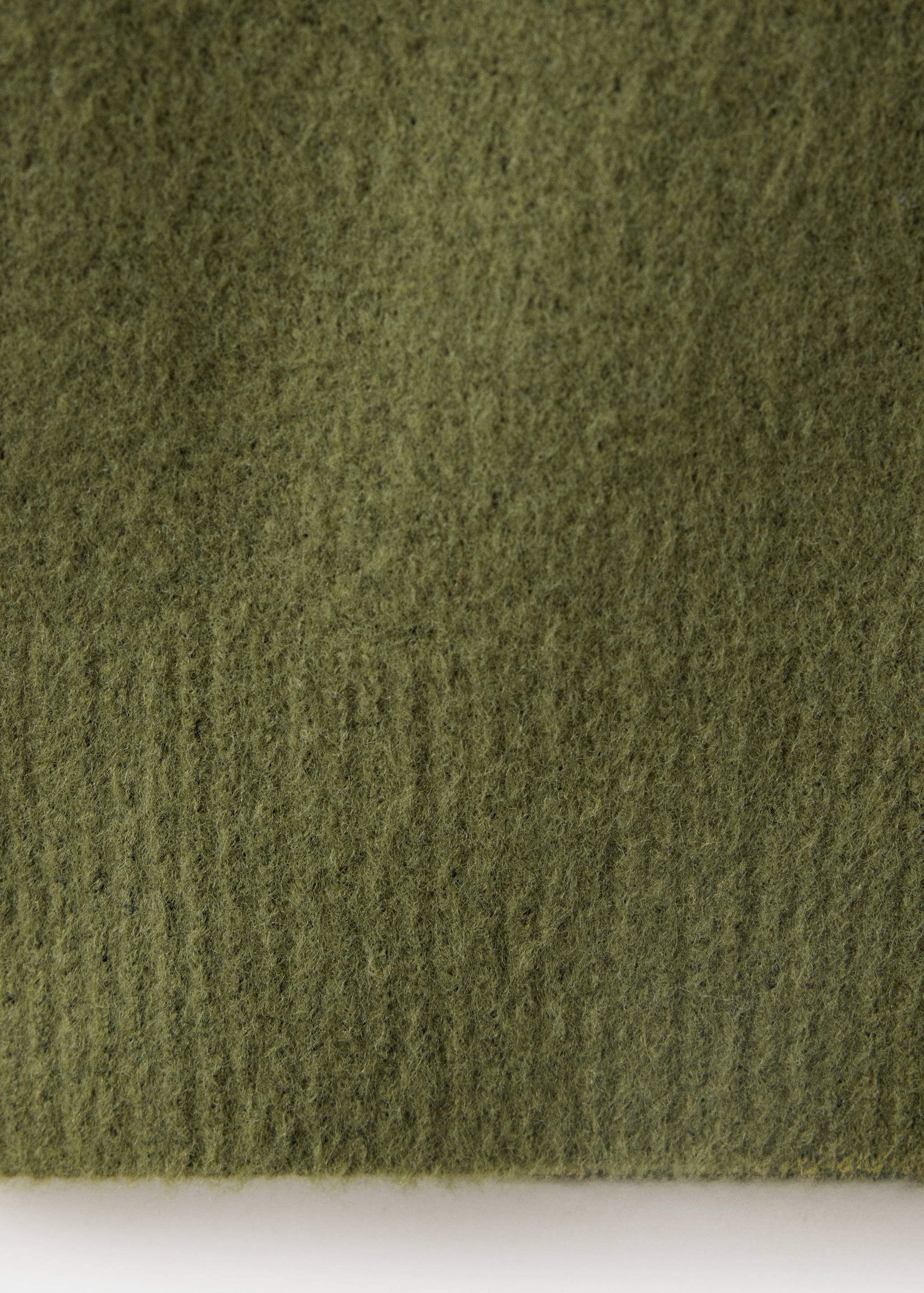 Green dress fabric detail showing a soft, brushed knit texture.