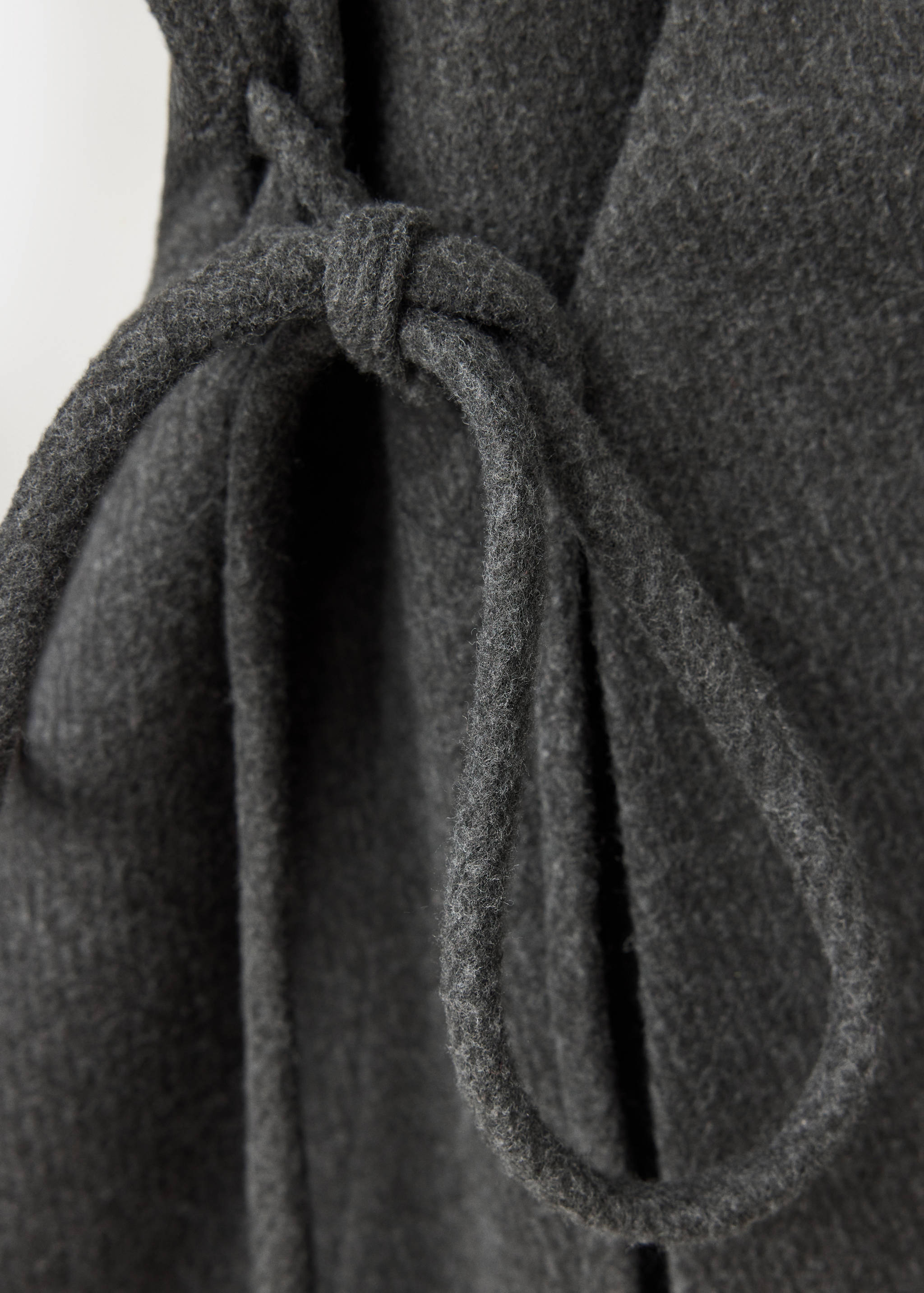 Close-up of a dark grey coat with a tied waist belt.