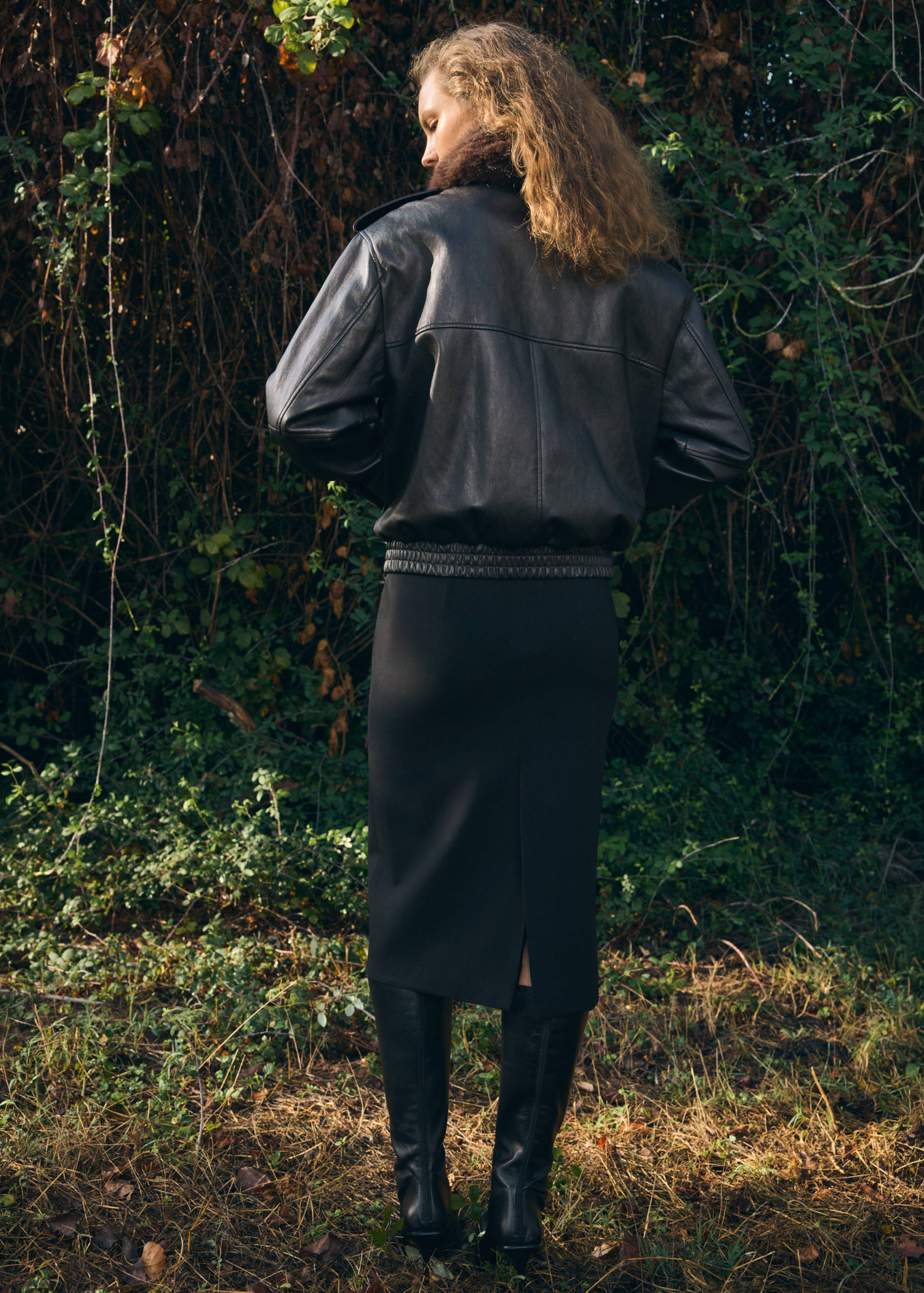 Black leather jacket with relaxed fit and faux-fur collar, back view.