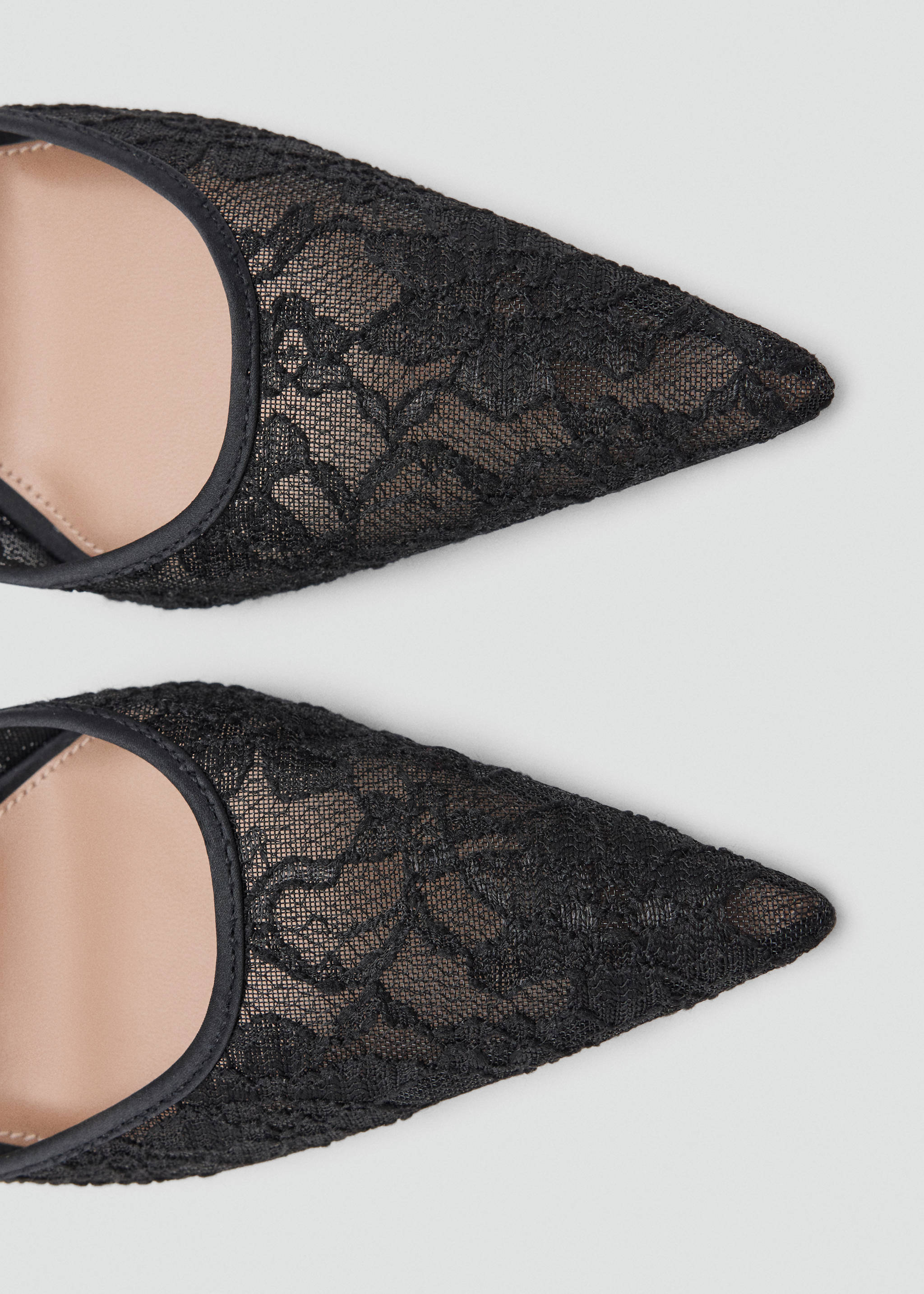 Close-up of black lace pointed-toe shoes.