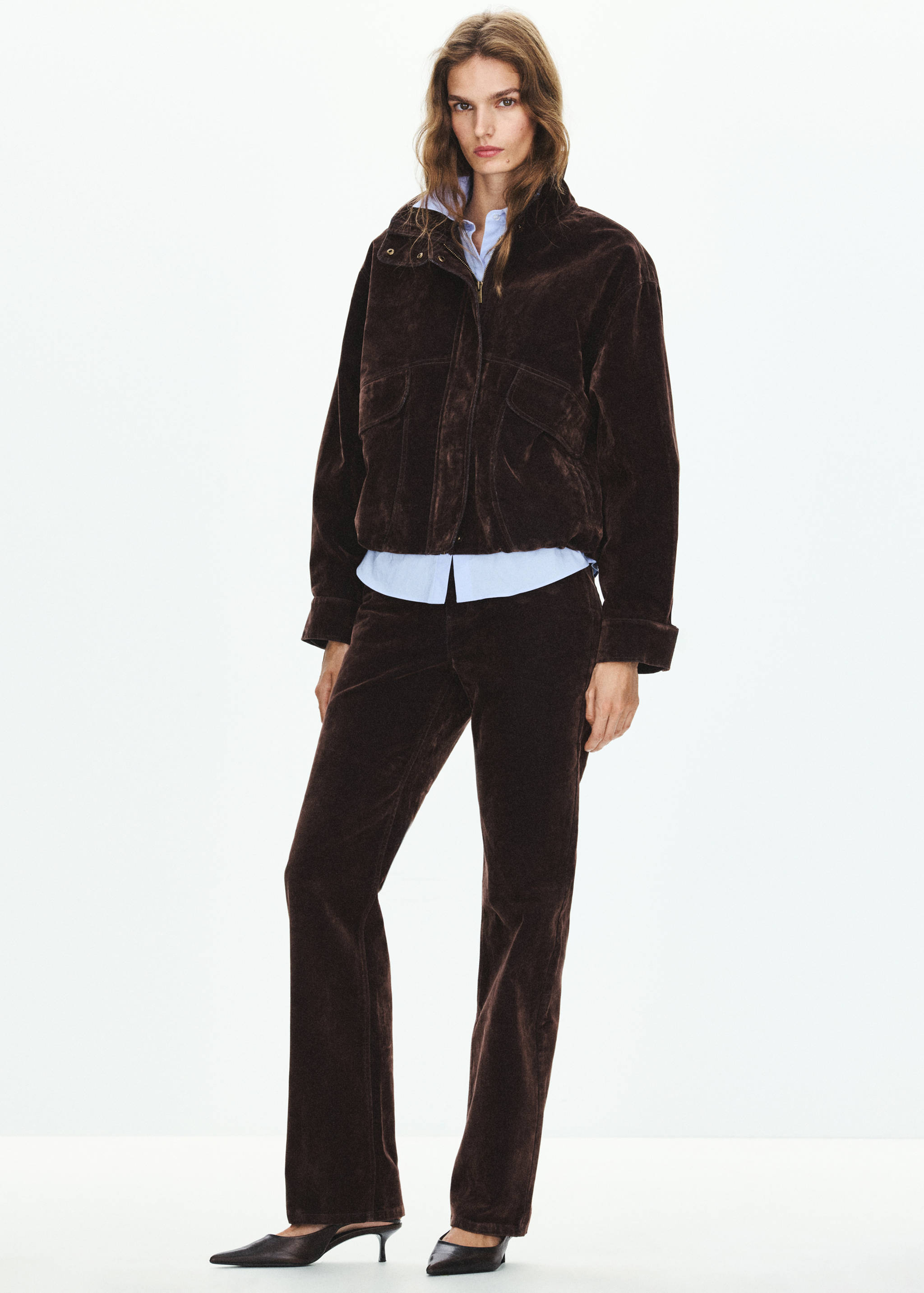 Dark brown corduroy jacket with high collar and chest pockets, worn over a blue shirt.
