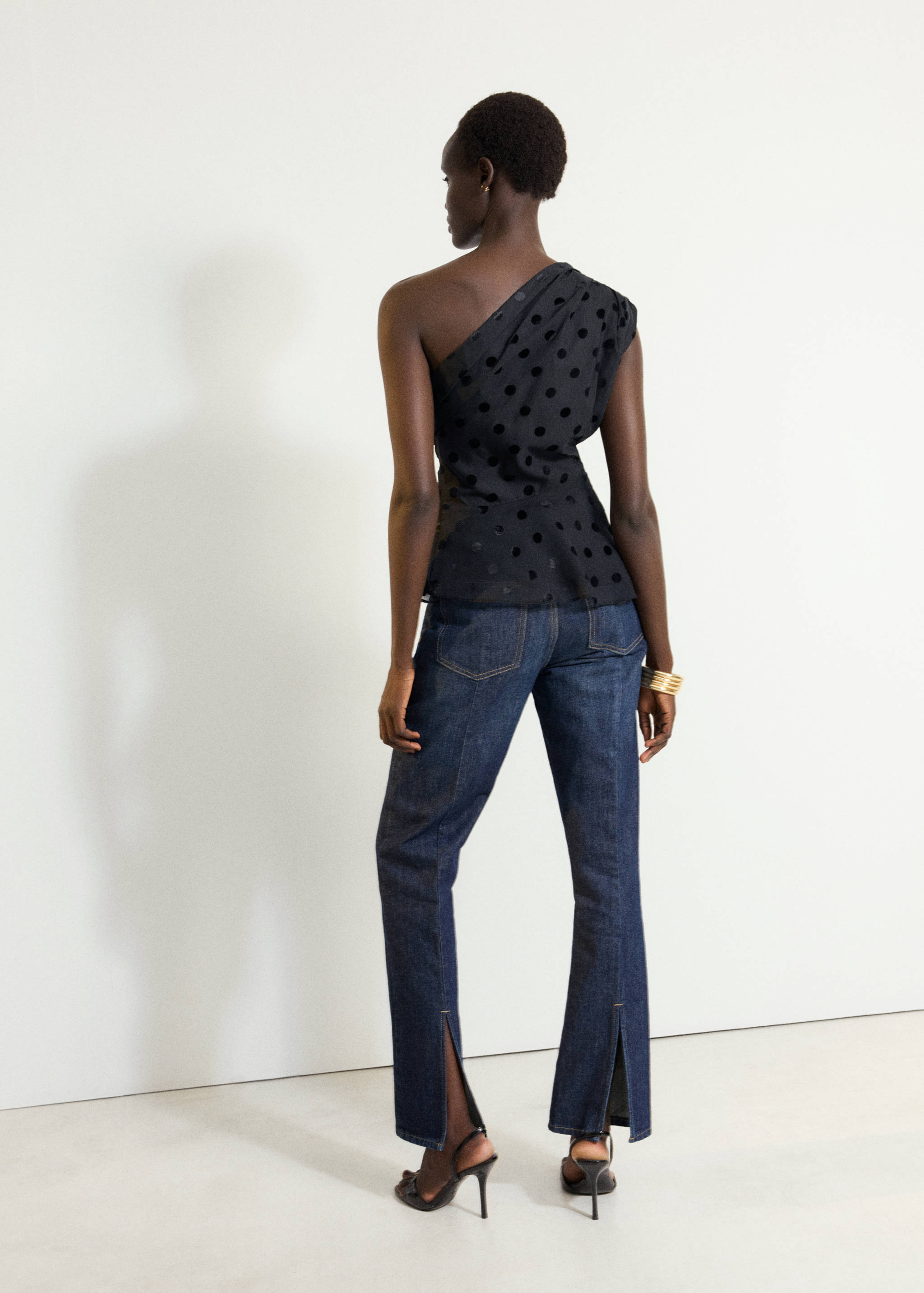 Black one-shoulder top with velvet polka dots, back view.