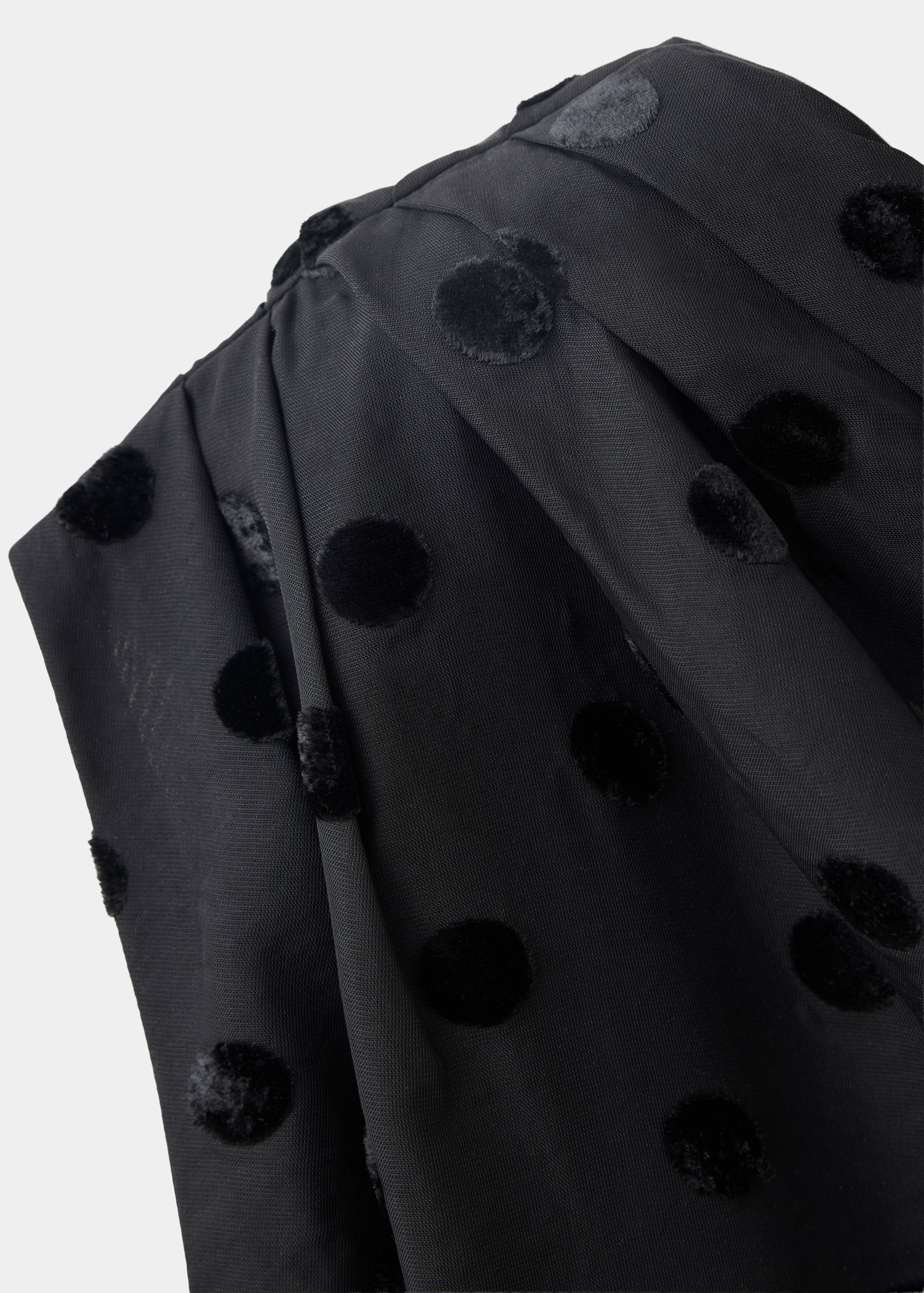 Close-up of a black top with velvet polka dots and pleating.
