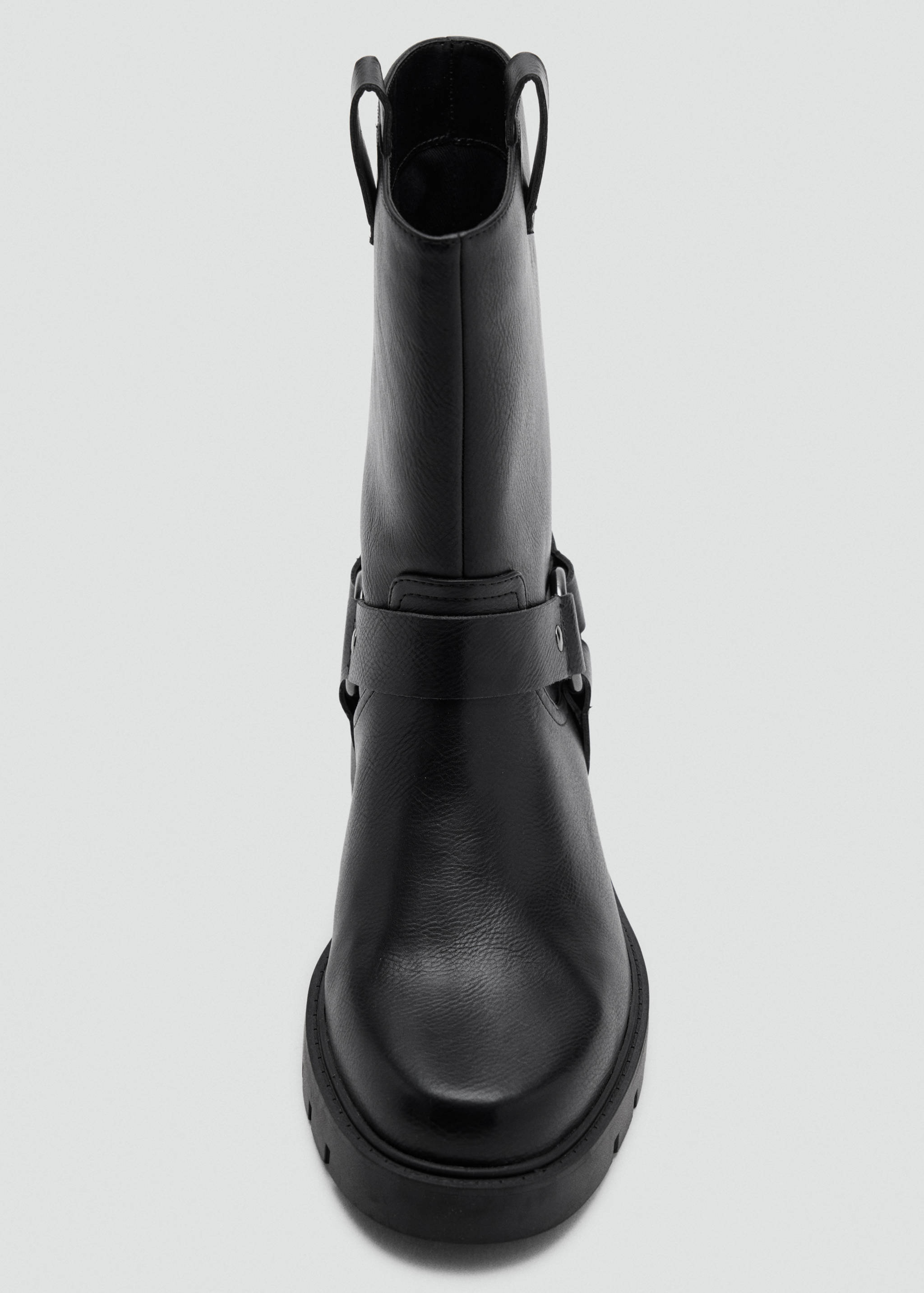 Black boot featuring an ankle harness and lug sole.