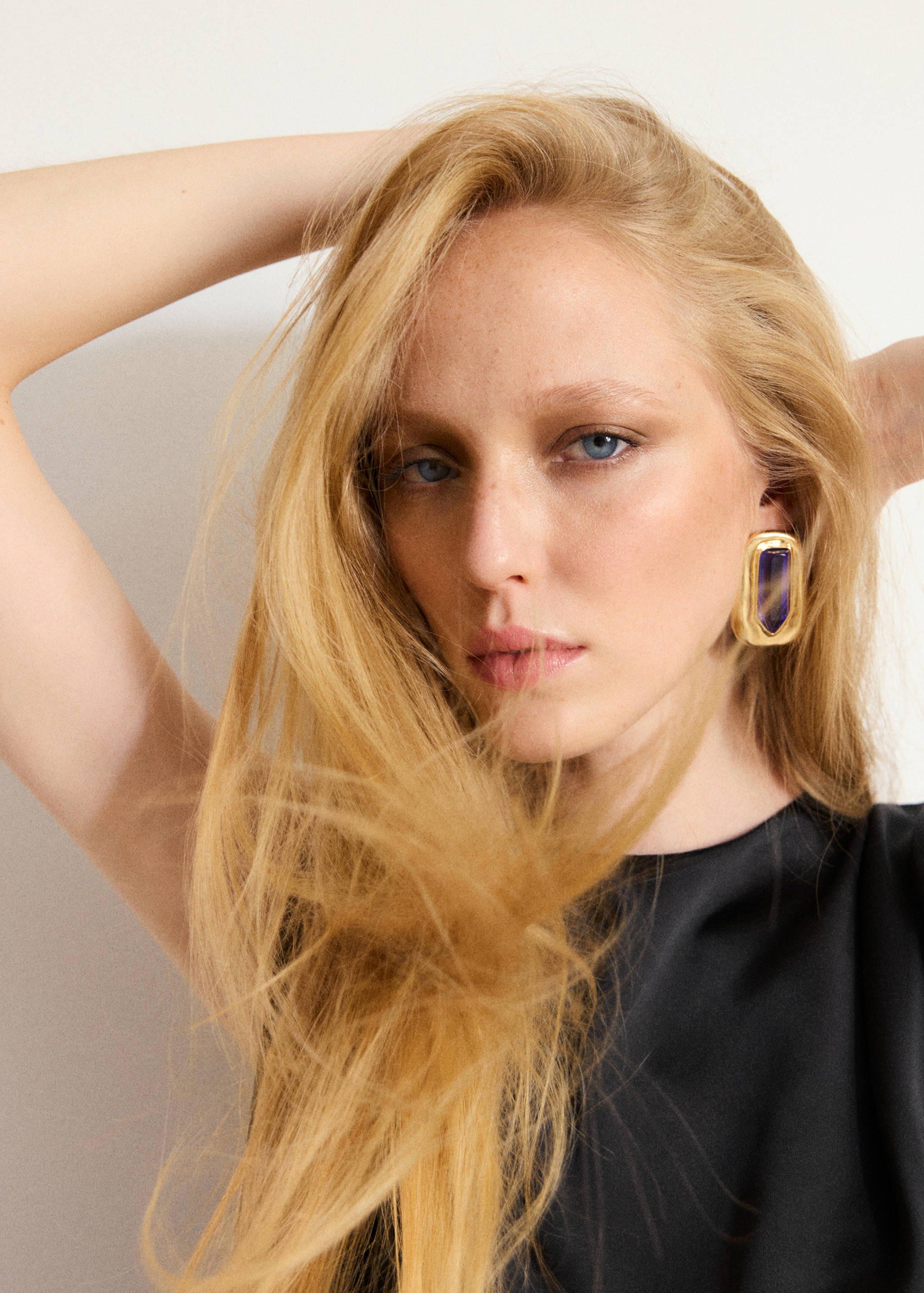 Close-up of a model wearing a black blouse and a large gold earring.