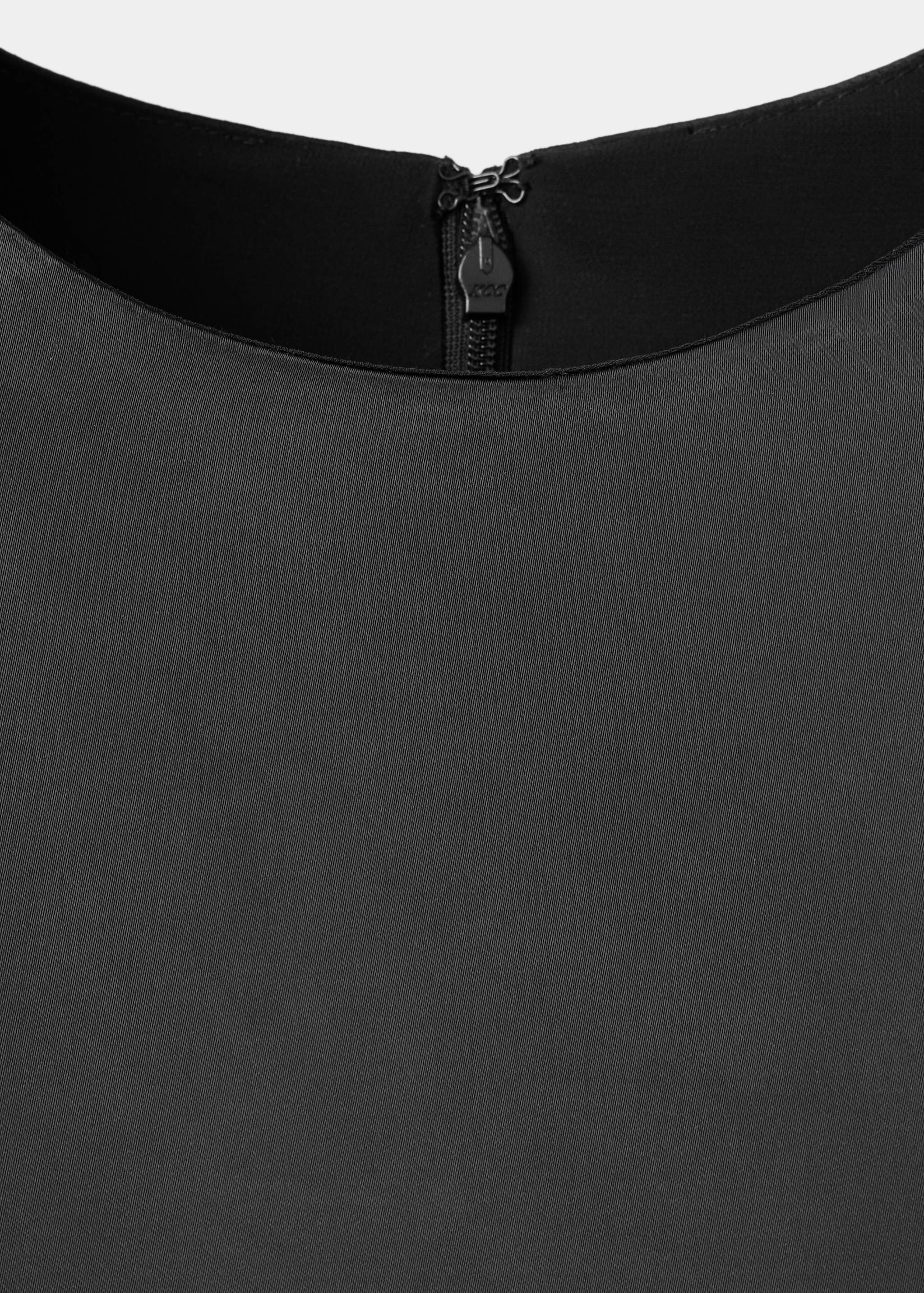 Close-up of a black blouse back neckline with a zip closure.