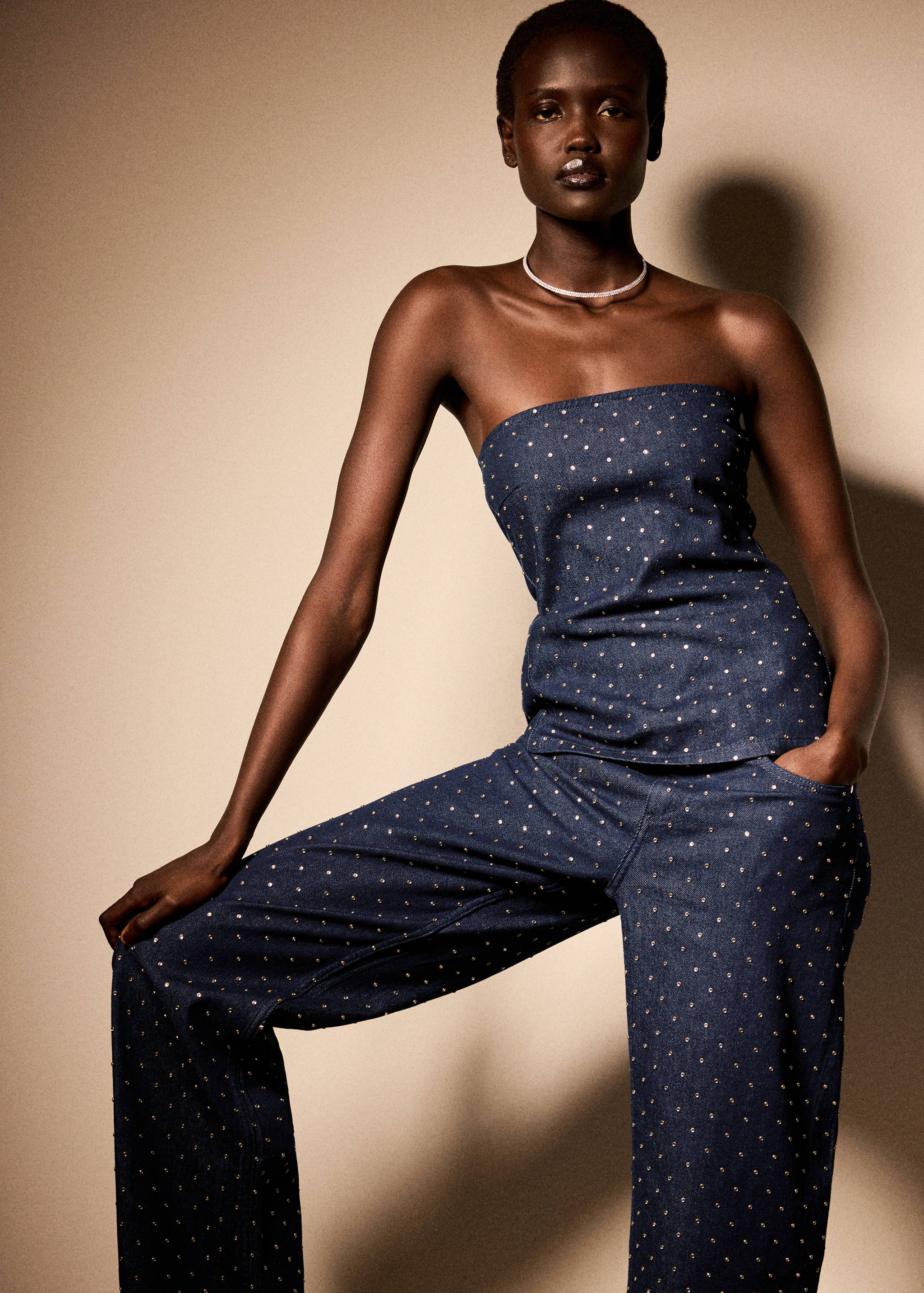 Denim bandeau top with gold studs and matching trousers, worn by a model.