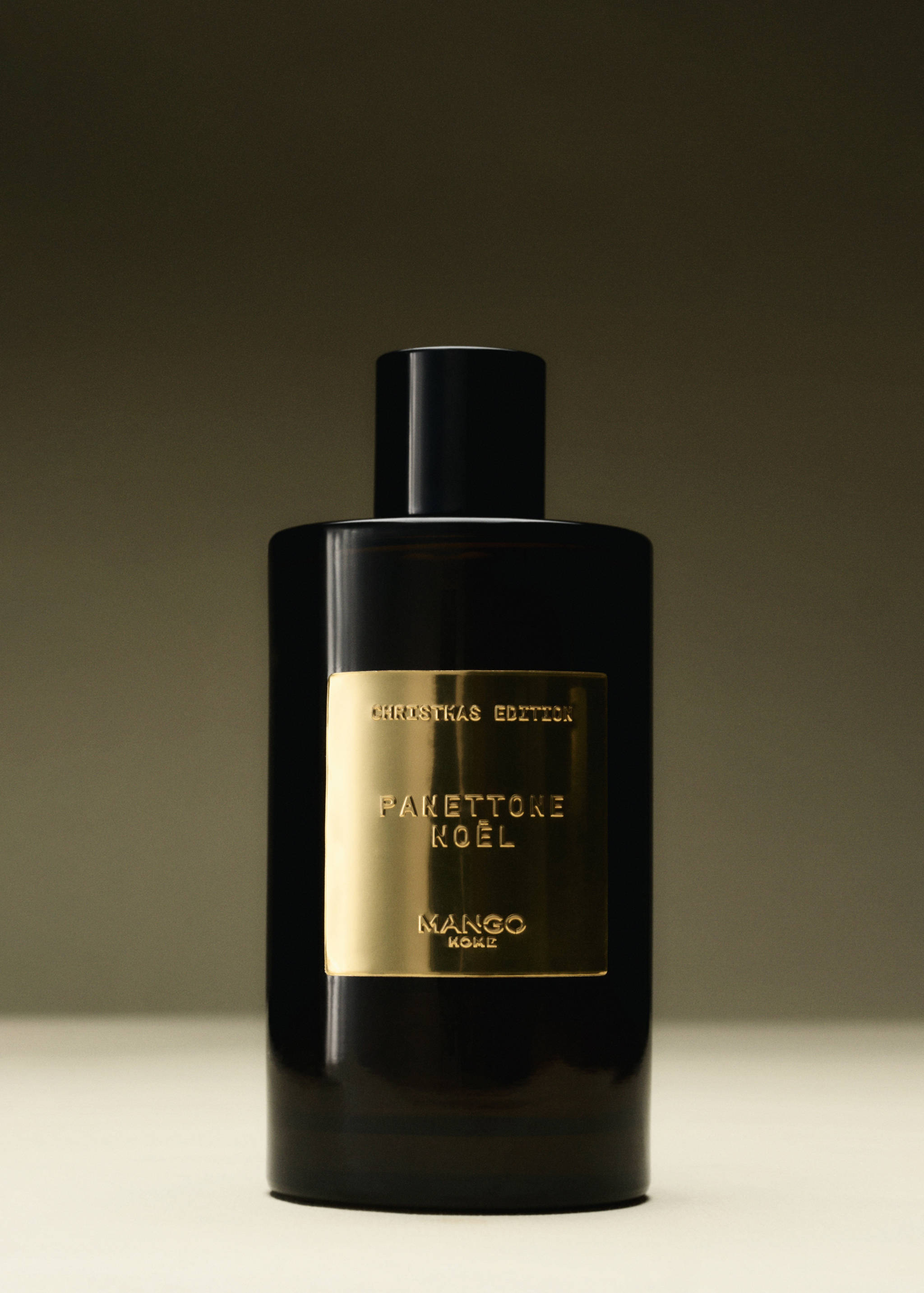 Dark home spray bottle with a gold label featuring black text.