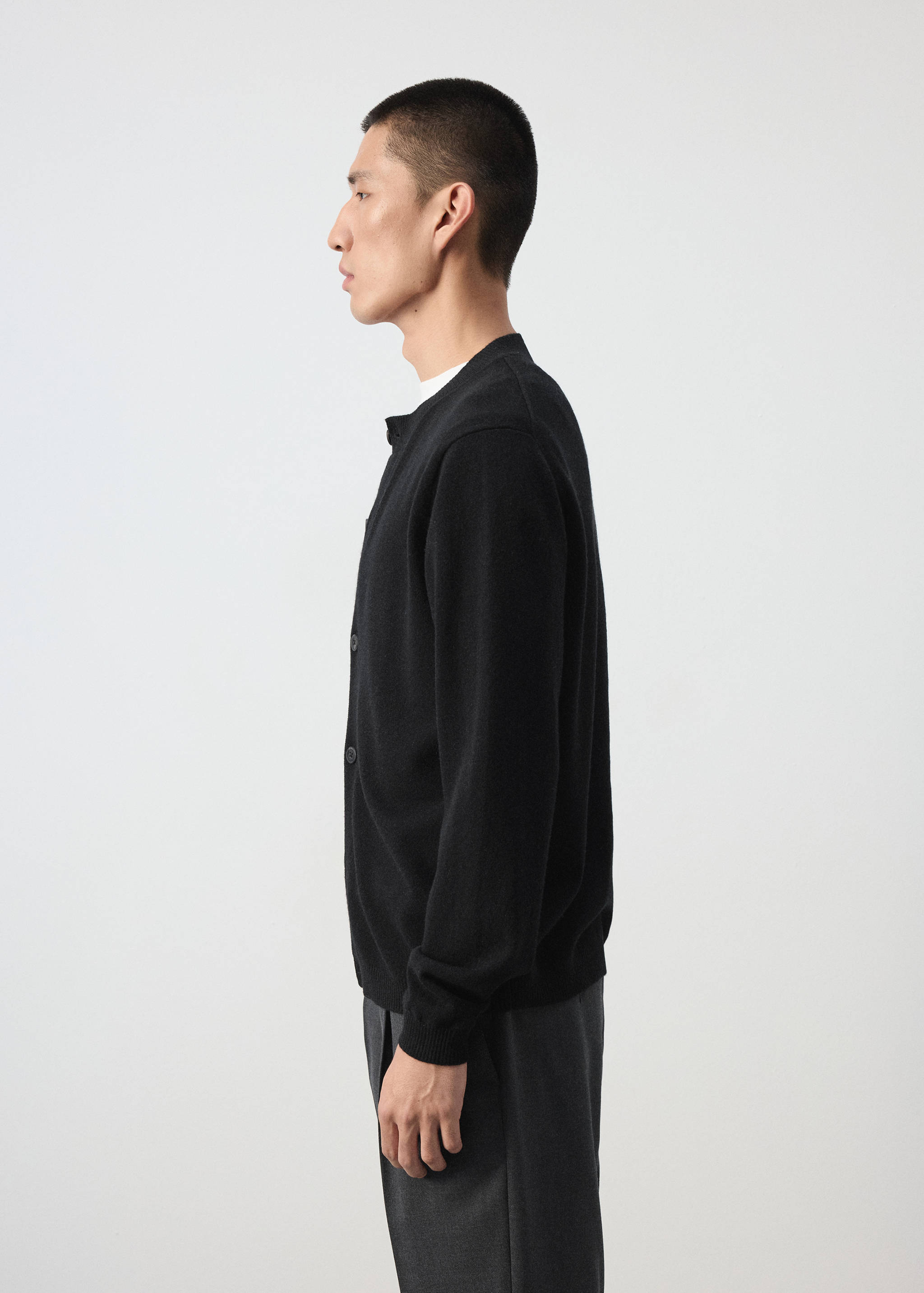 Black long-sleeved knit cardigan with button fastening and round neckline.