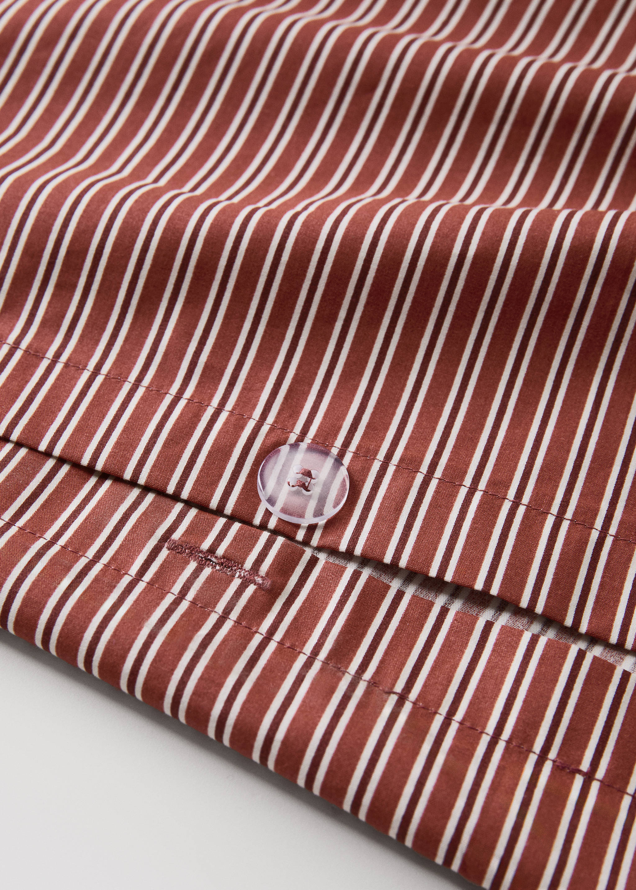 Brown and white striped duvet cover button detail.