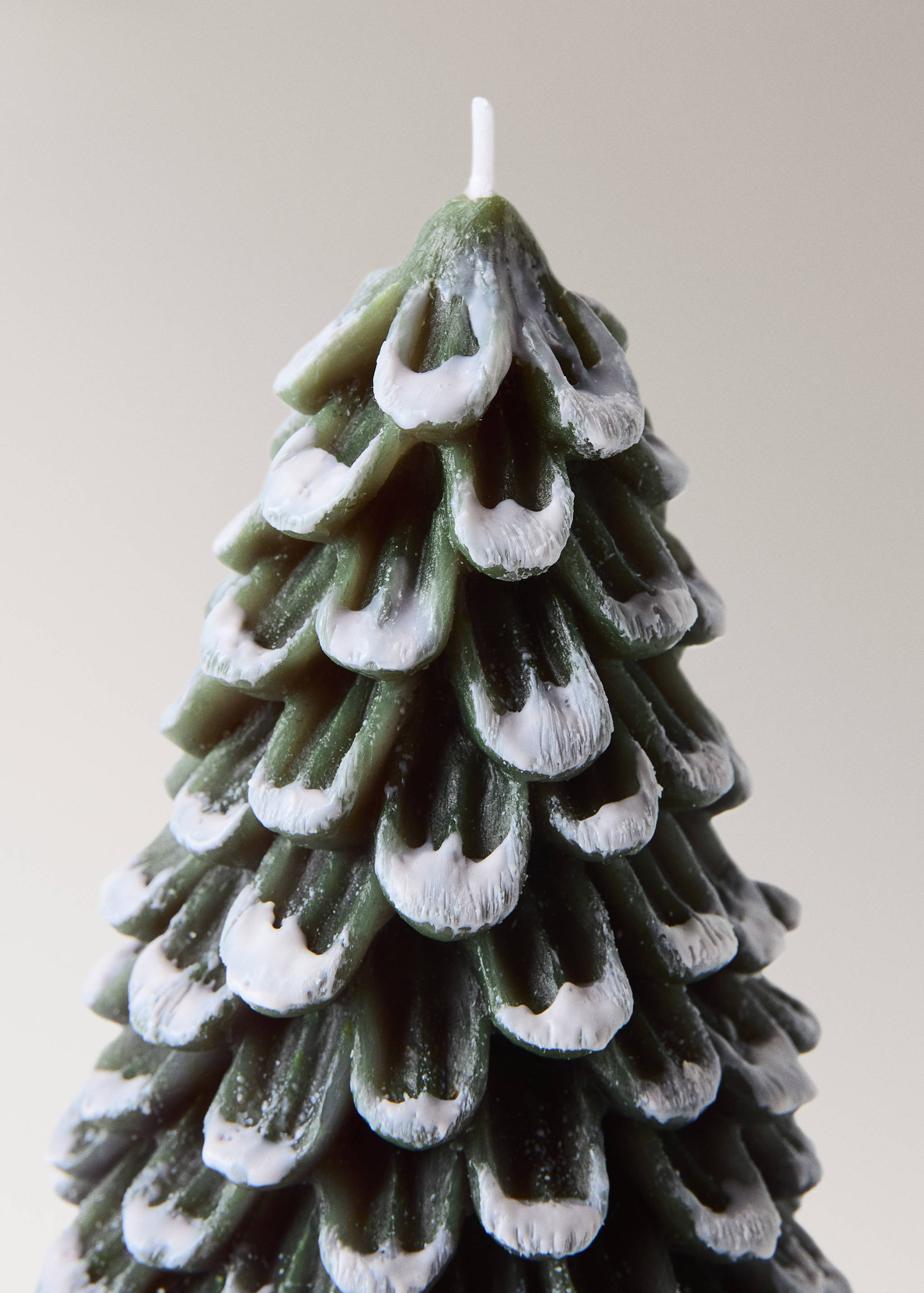 Close-up of a green pine-shaped candle with white-tipped details.