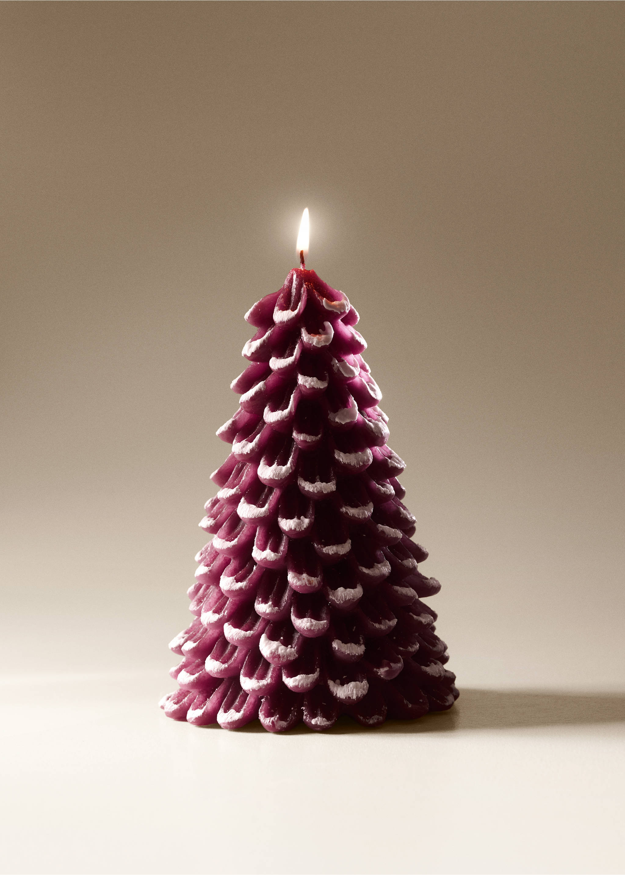 Dark purple tree-shaped candle with snow-effect white tips and a lit wick., Maroon. Ref: 37067892-00.