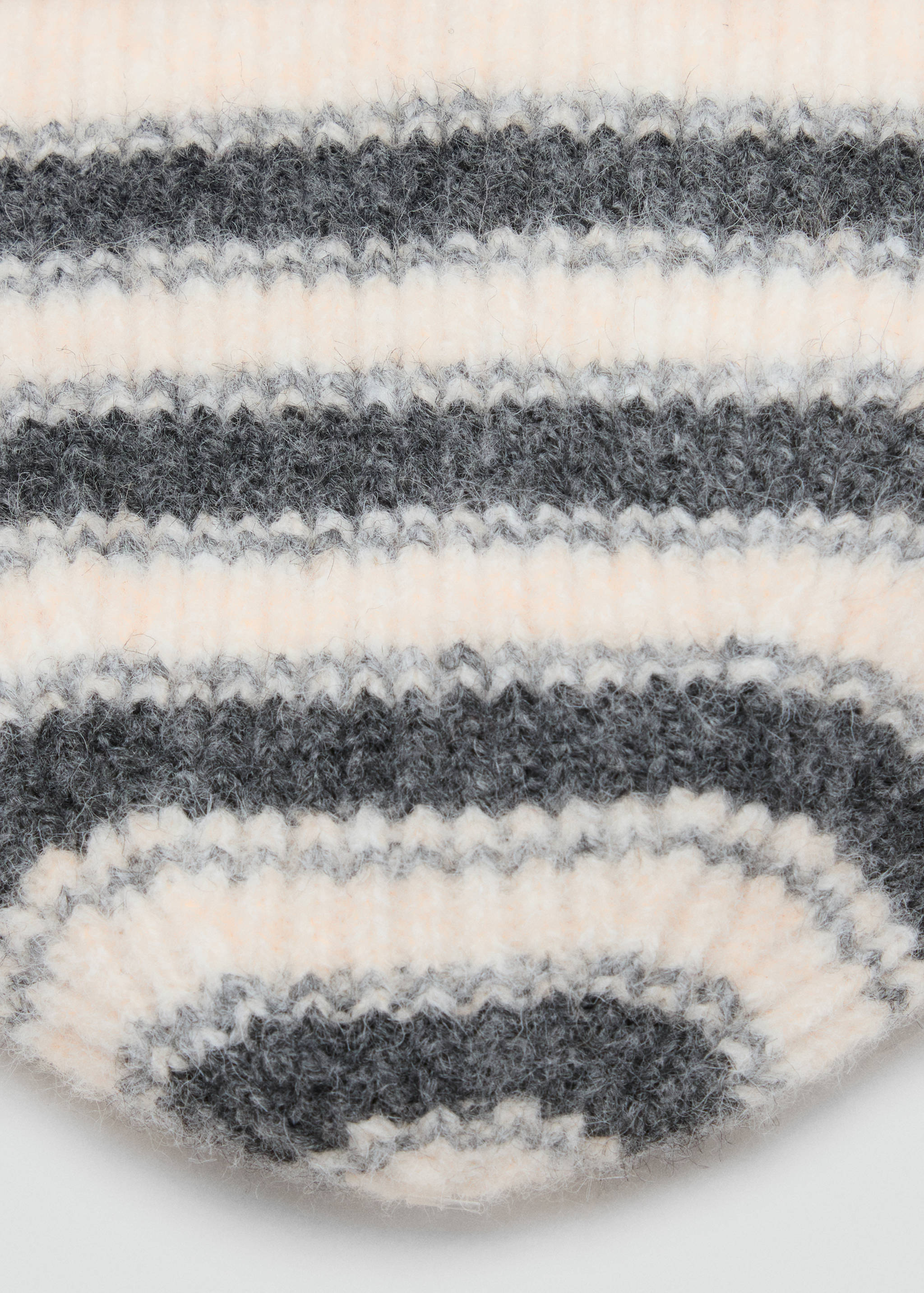 Close-up of a fuzzy, striped knit hat in grey, white, and pale peach.