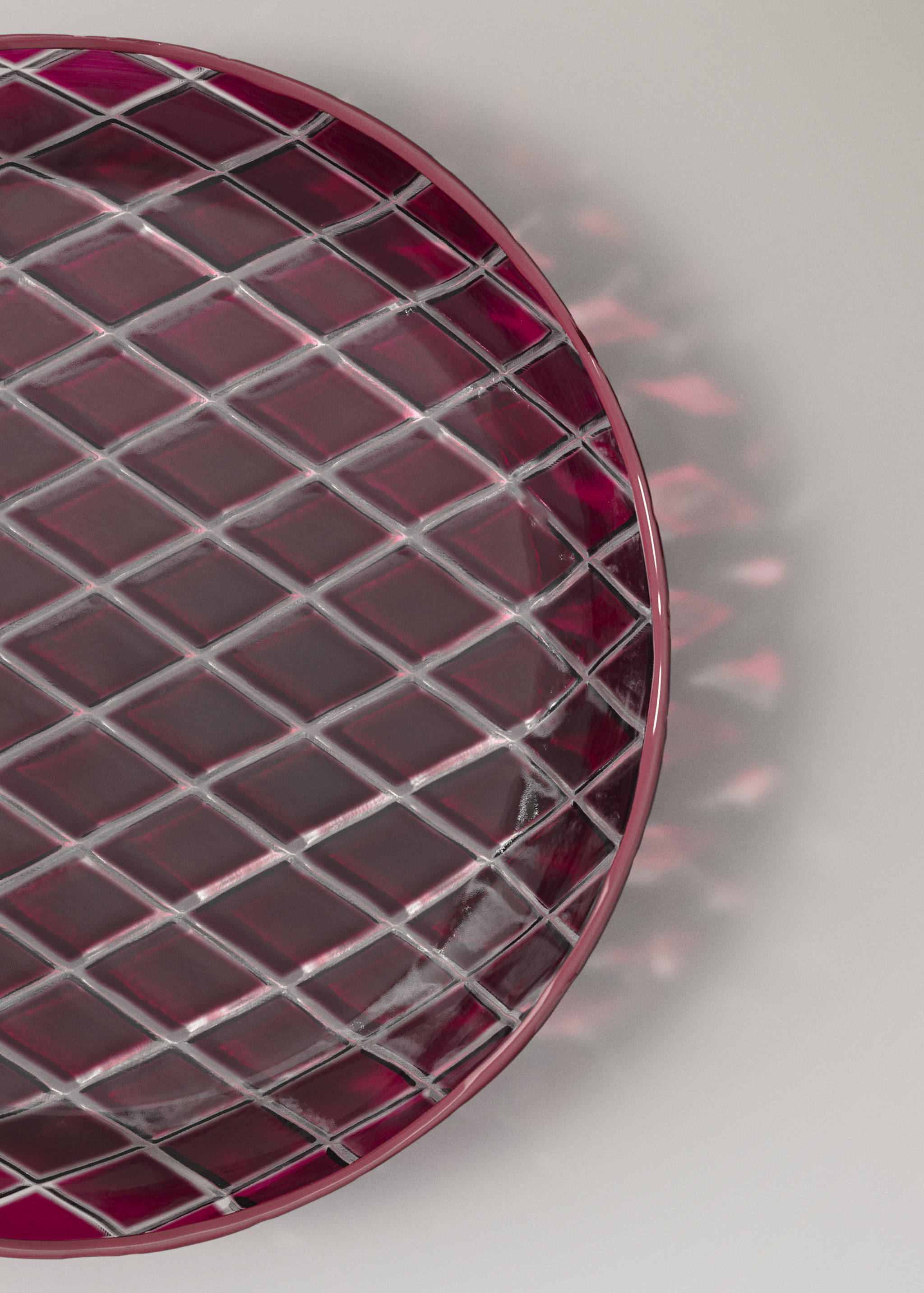 Close-up of a deep magenta glass plate with a faceted diamond pattern.