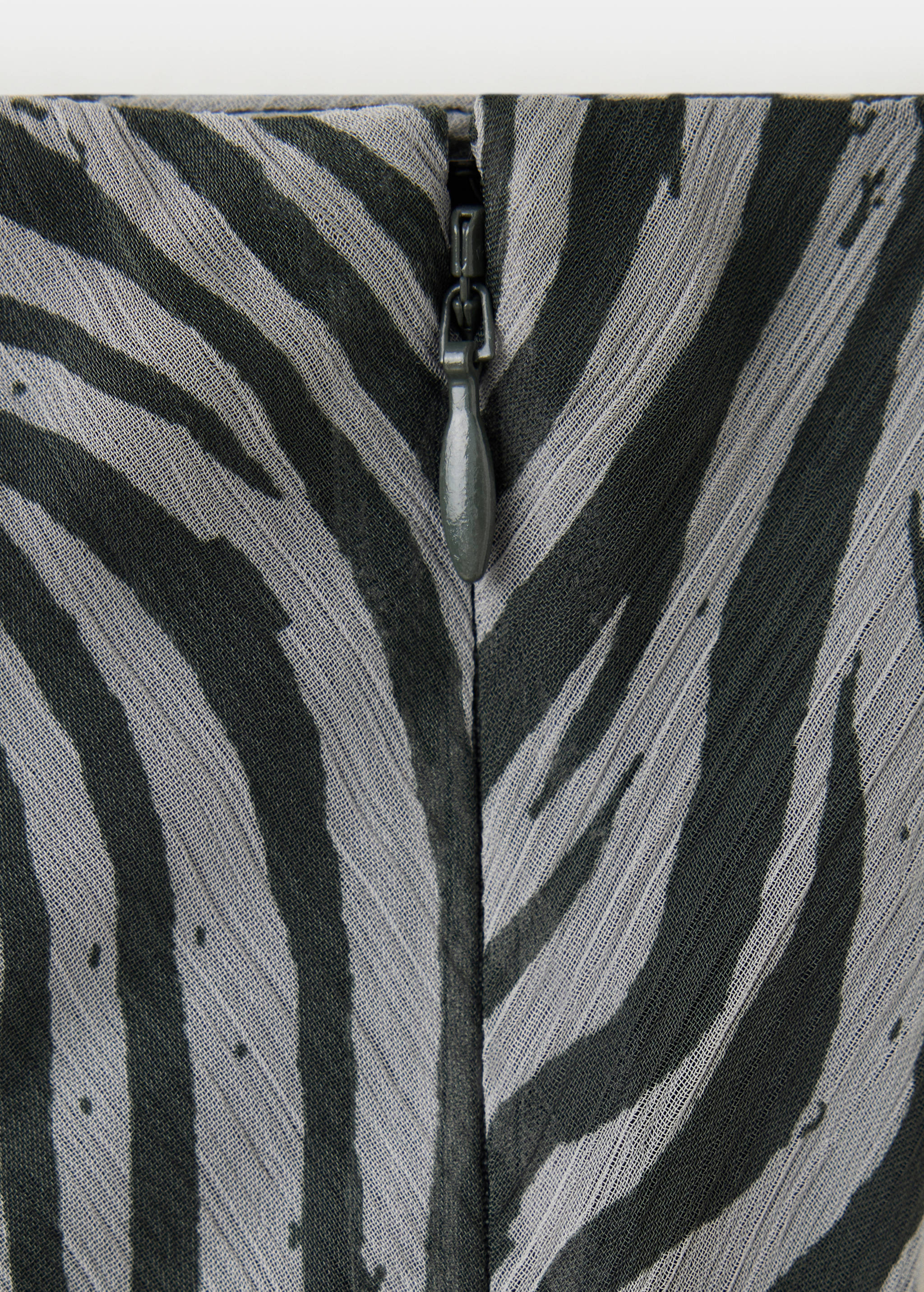 Close-up of a skirt's zipper closure in black and grey animal print.