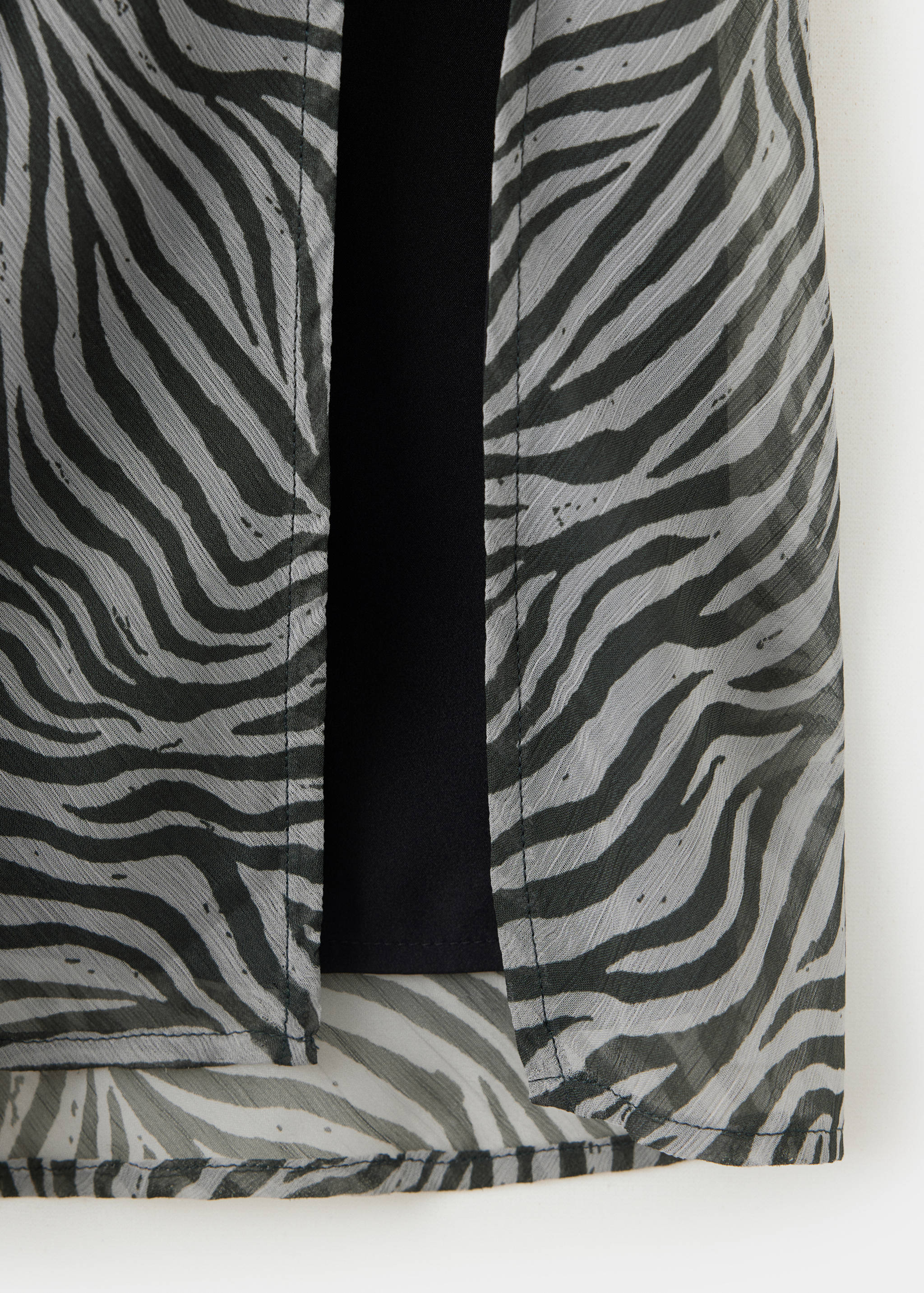 Close-up of a grey and black zebra-print skirt with a sheer fabric detail.