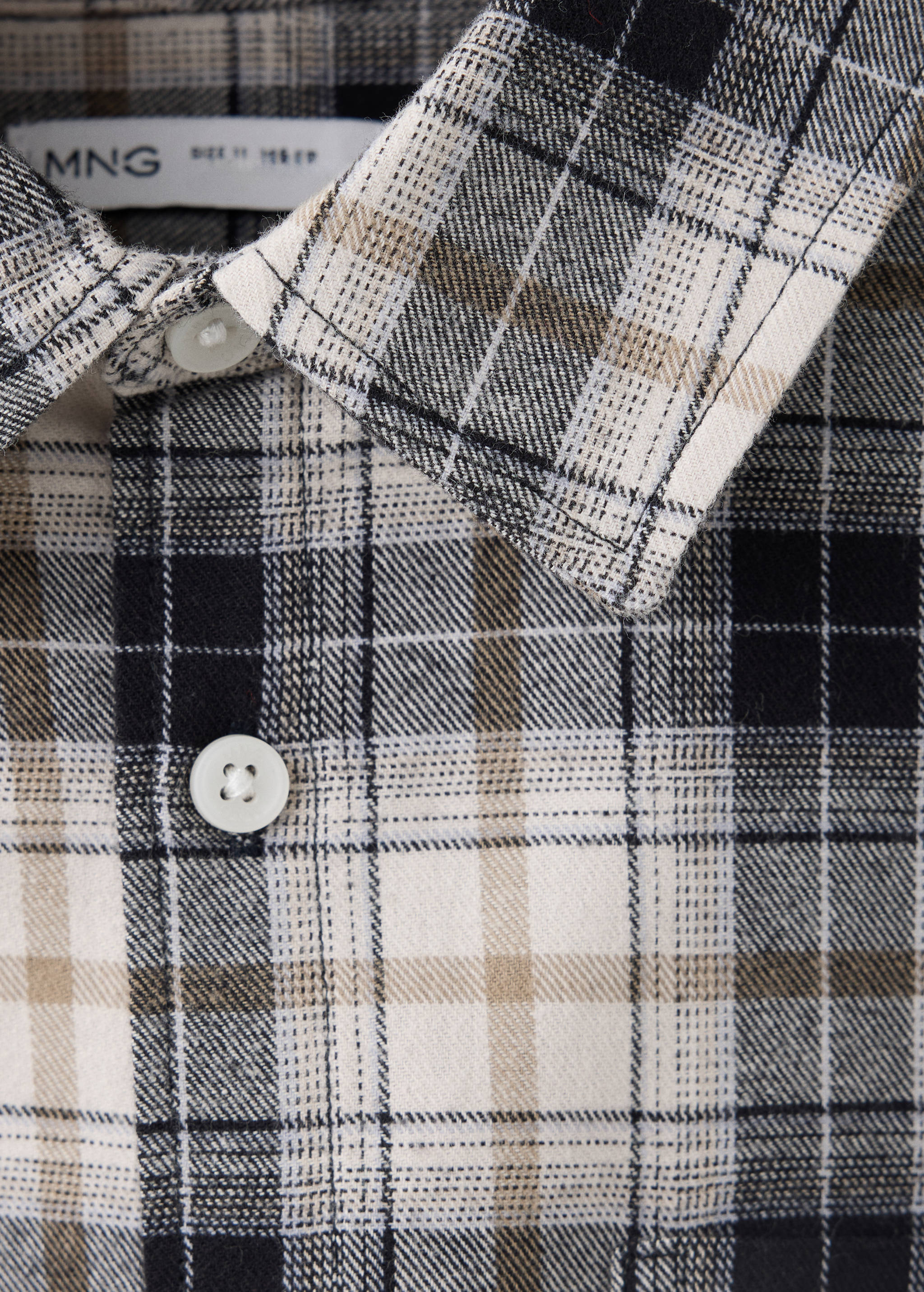 Close-up of a black, off-white, and beige plaid children's shirt with a collar and button placket.