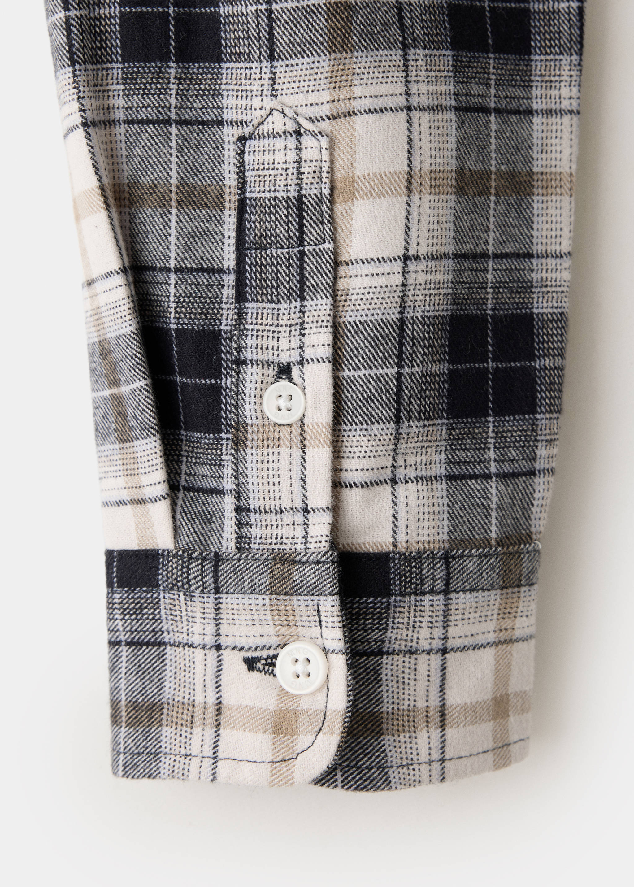 Checkered shirt sleeve detail in black, white, and tan with white buttons.