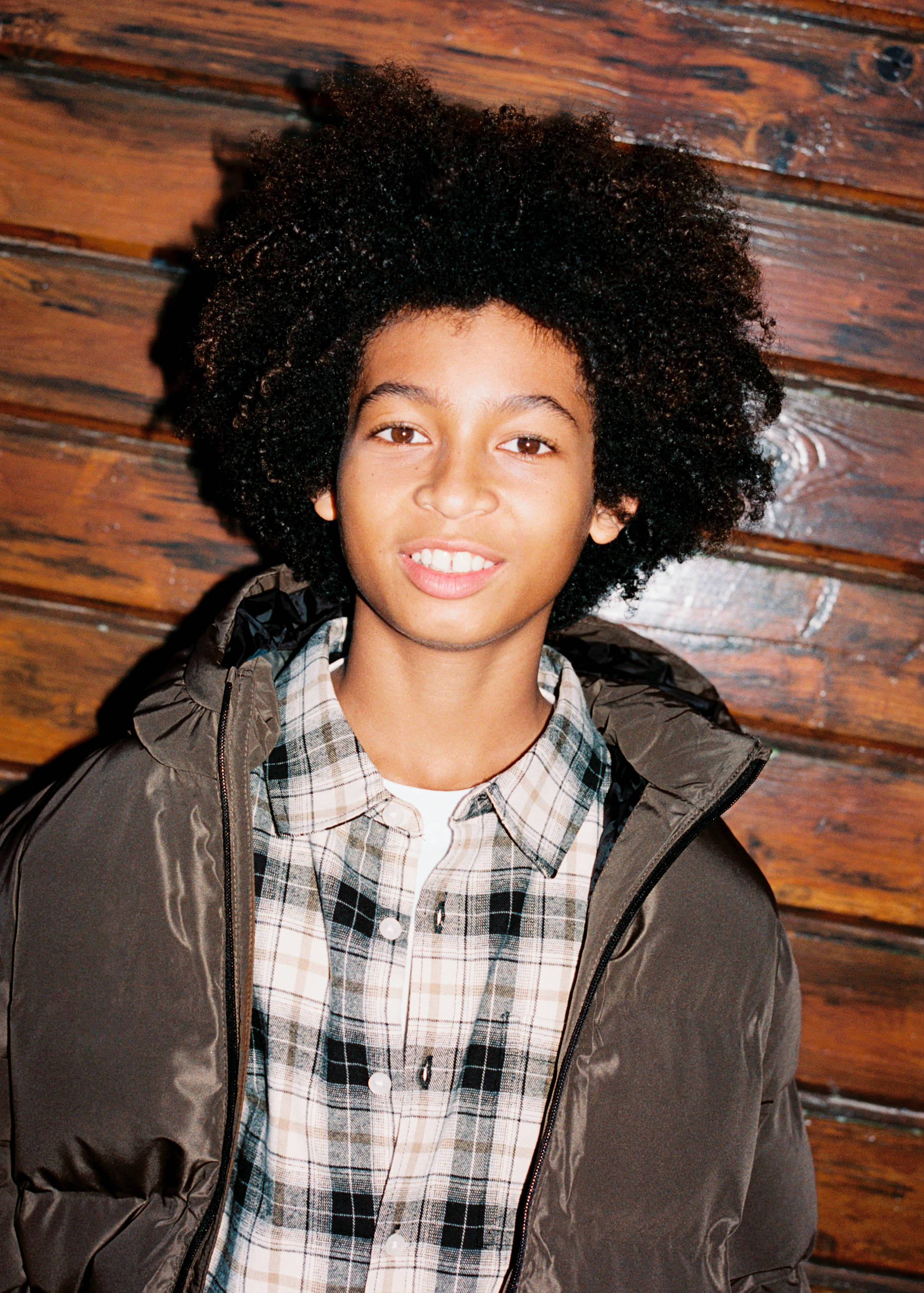 Check plaid shirt with collar and button fastening worn under a puffer jacket.