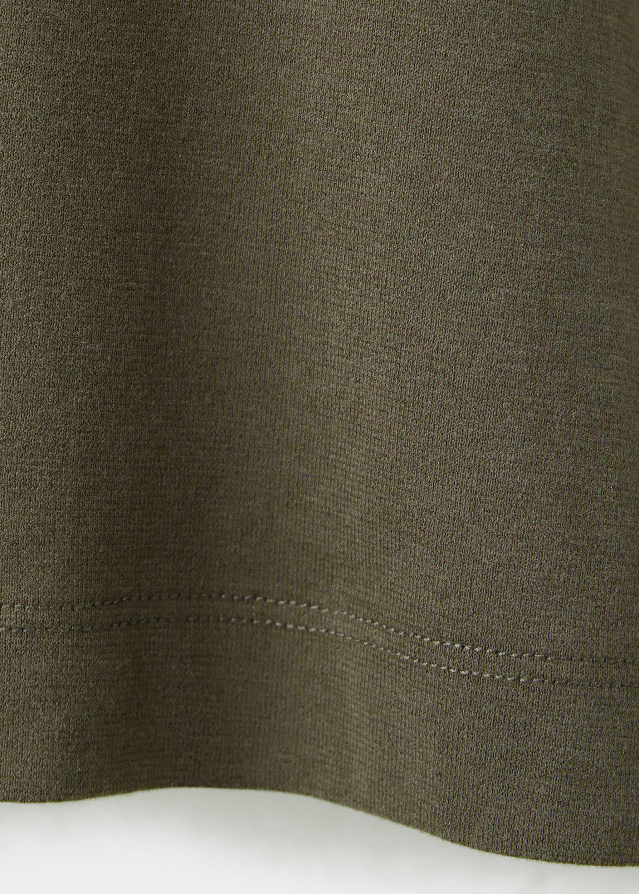 Close-up of olive green t-shirt fabric texture and hem.