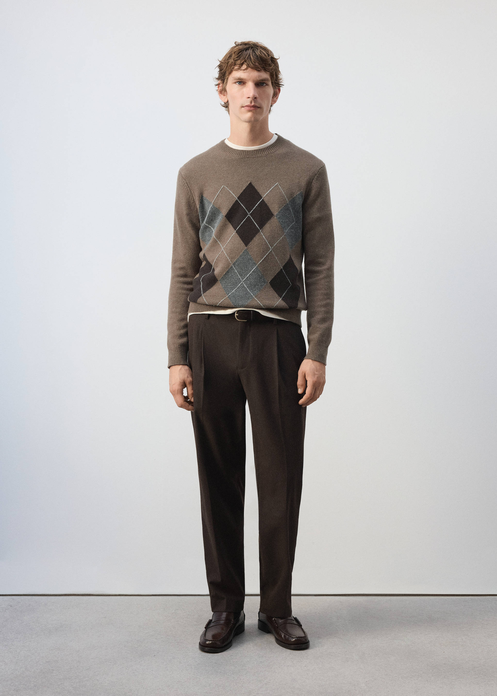 Brown knit argyle jersey with a crew neck, styled with dark brown trousers.
