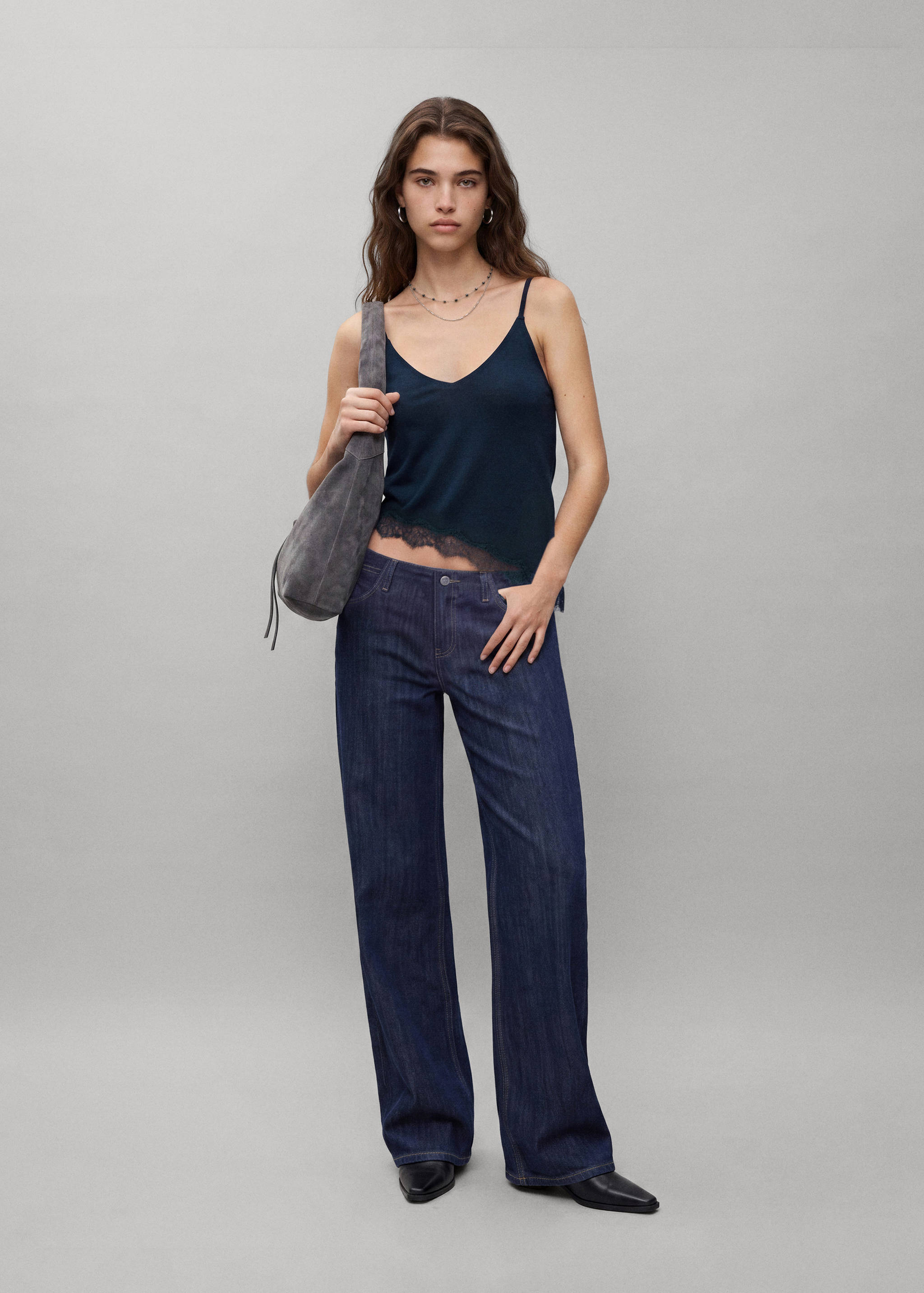 Dark blue V-neck camisole top with lace trim, worn with wide-leg trousers.