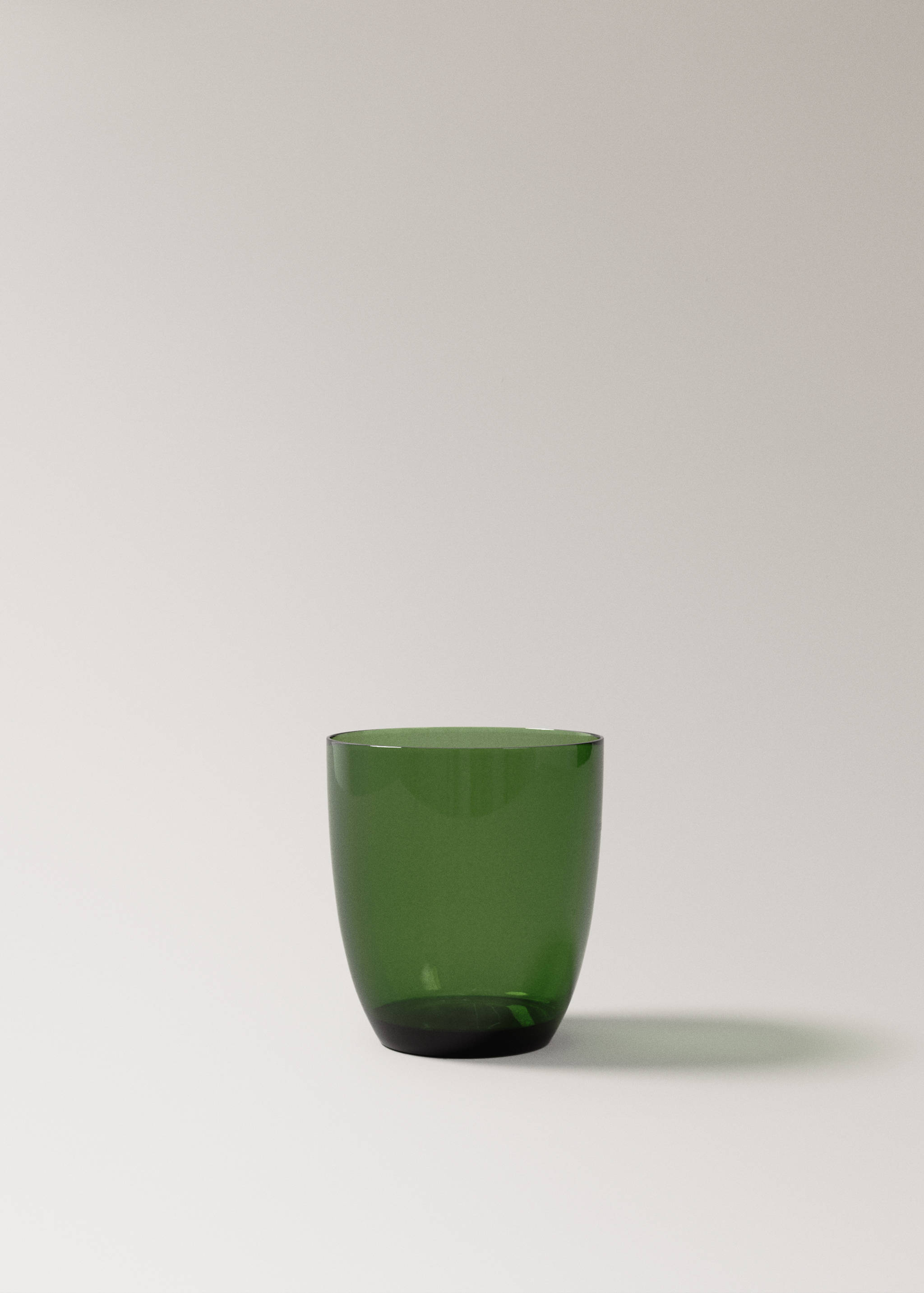 Green glass tumbler in a still-life setup.
