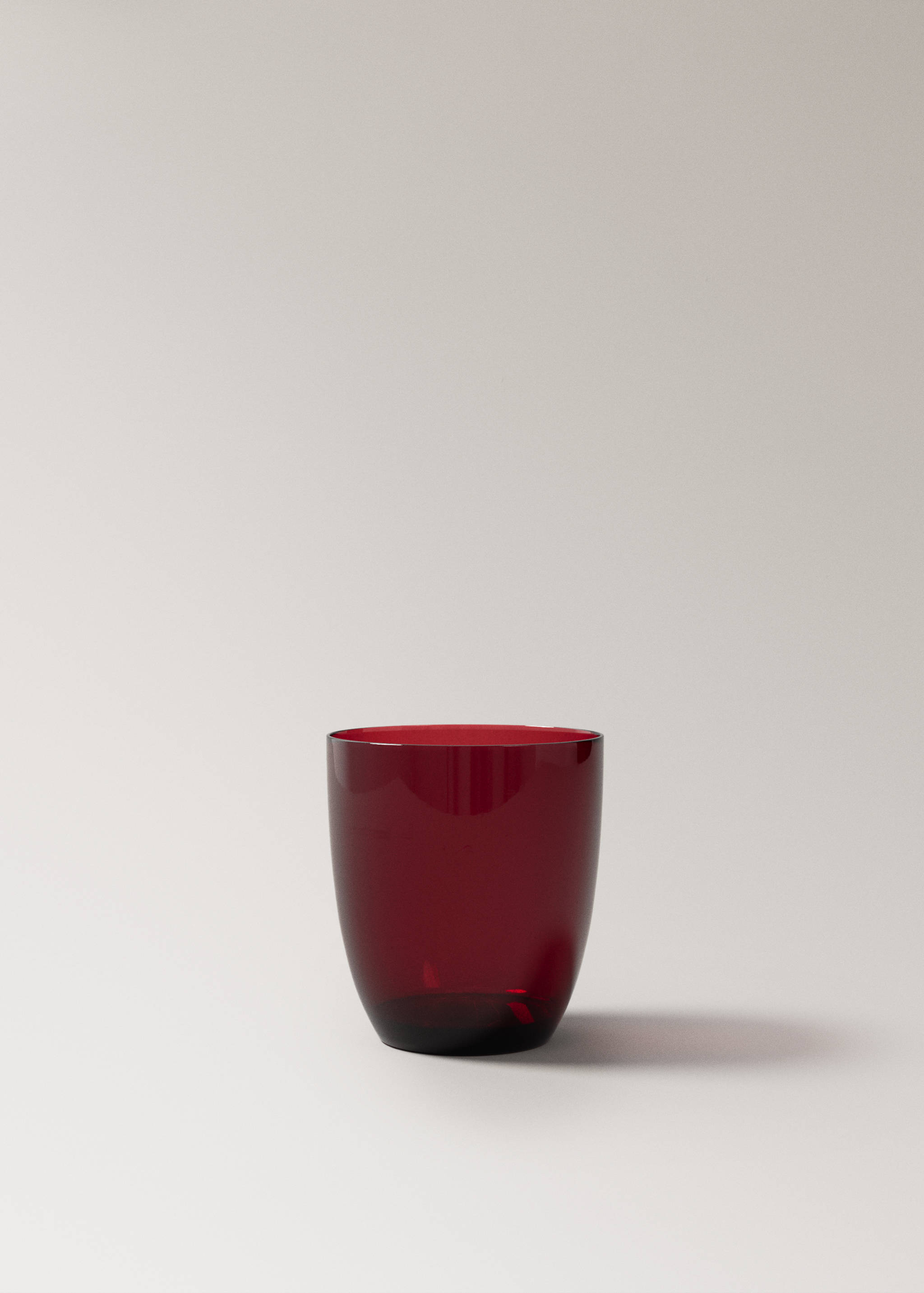 Red glass tumbler on a neutral background.