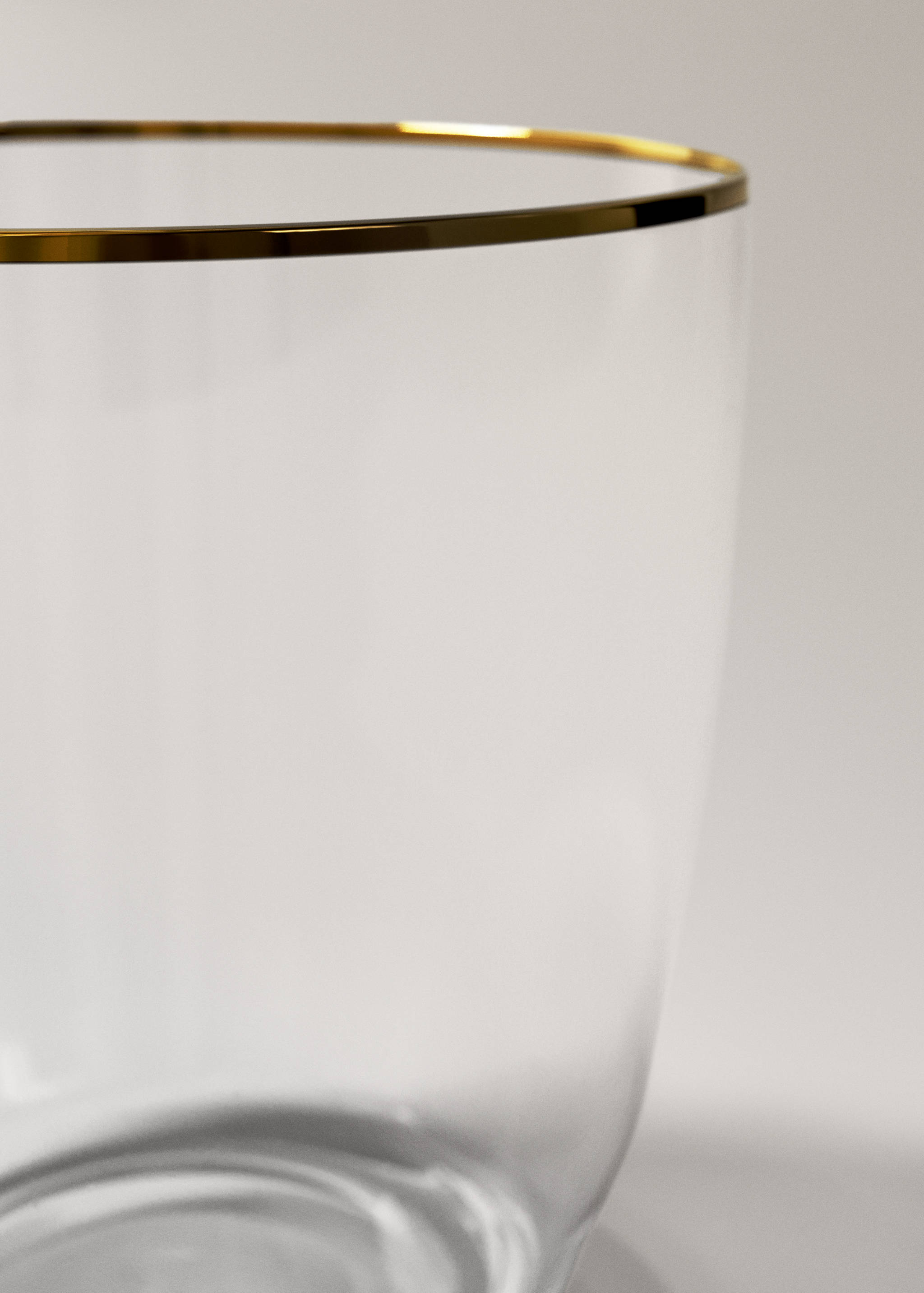 Close-up of a clear glass tumbler with a gold-coloured rim.