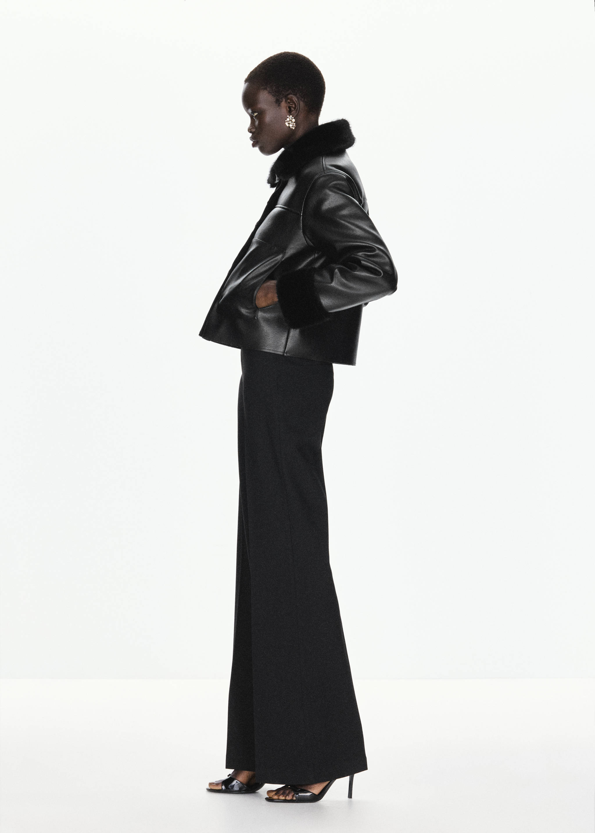 Black jacket with faux-fur collar and cuffs, worn with black trousers.