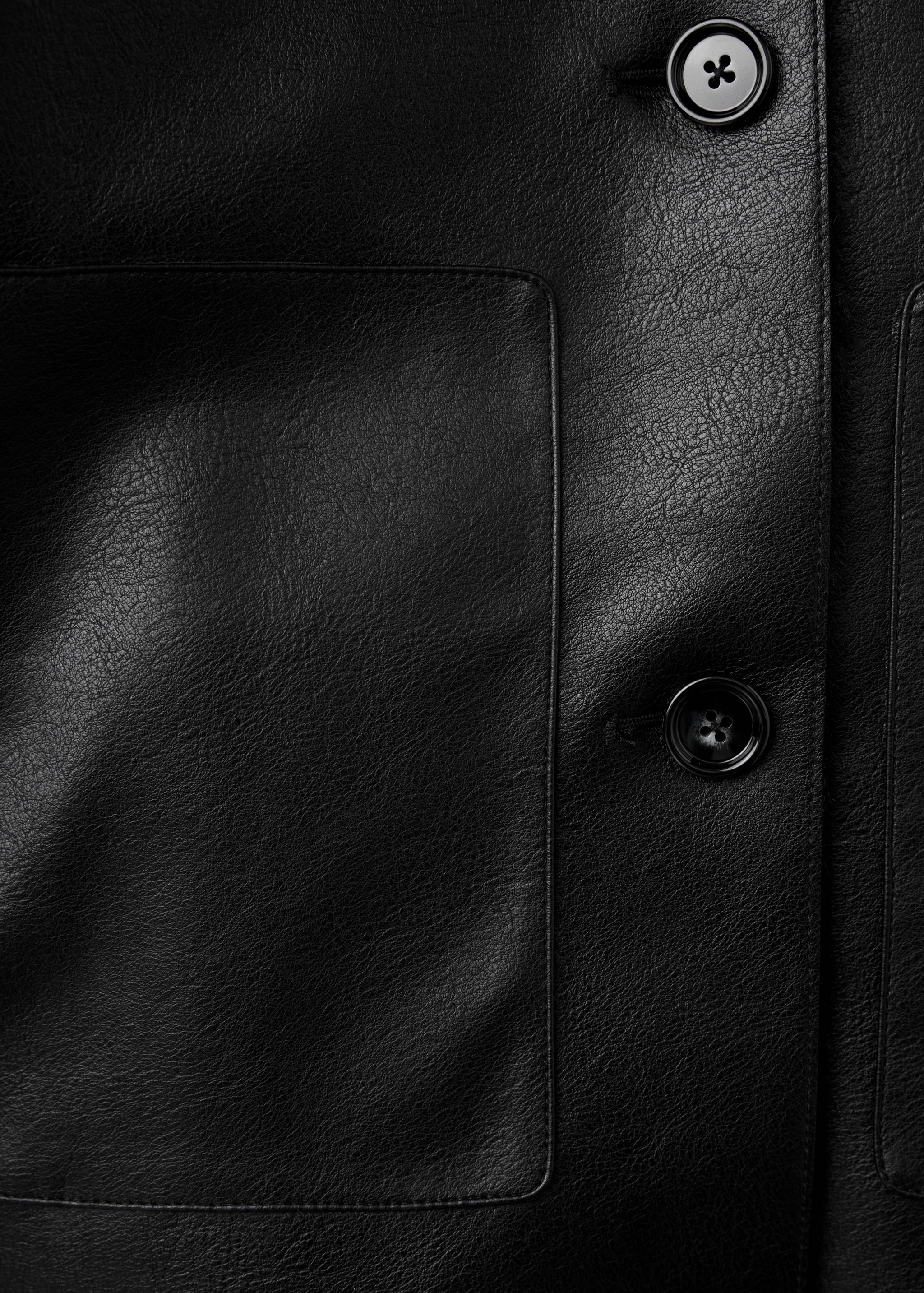 Black jacket detail showing buttons and patch pocket.