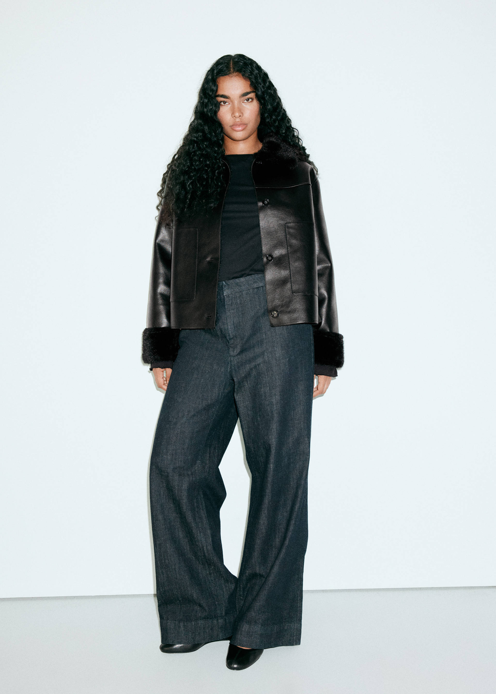 Black jacket with faux-fur collar and cuffs, worn with dark trousers.