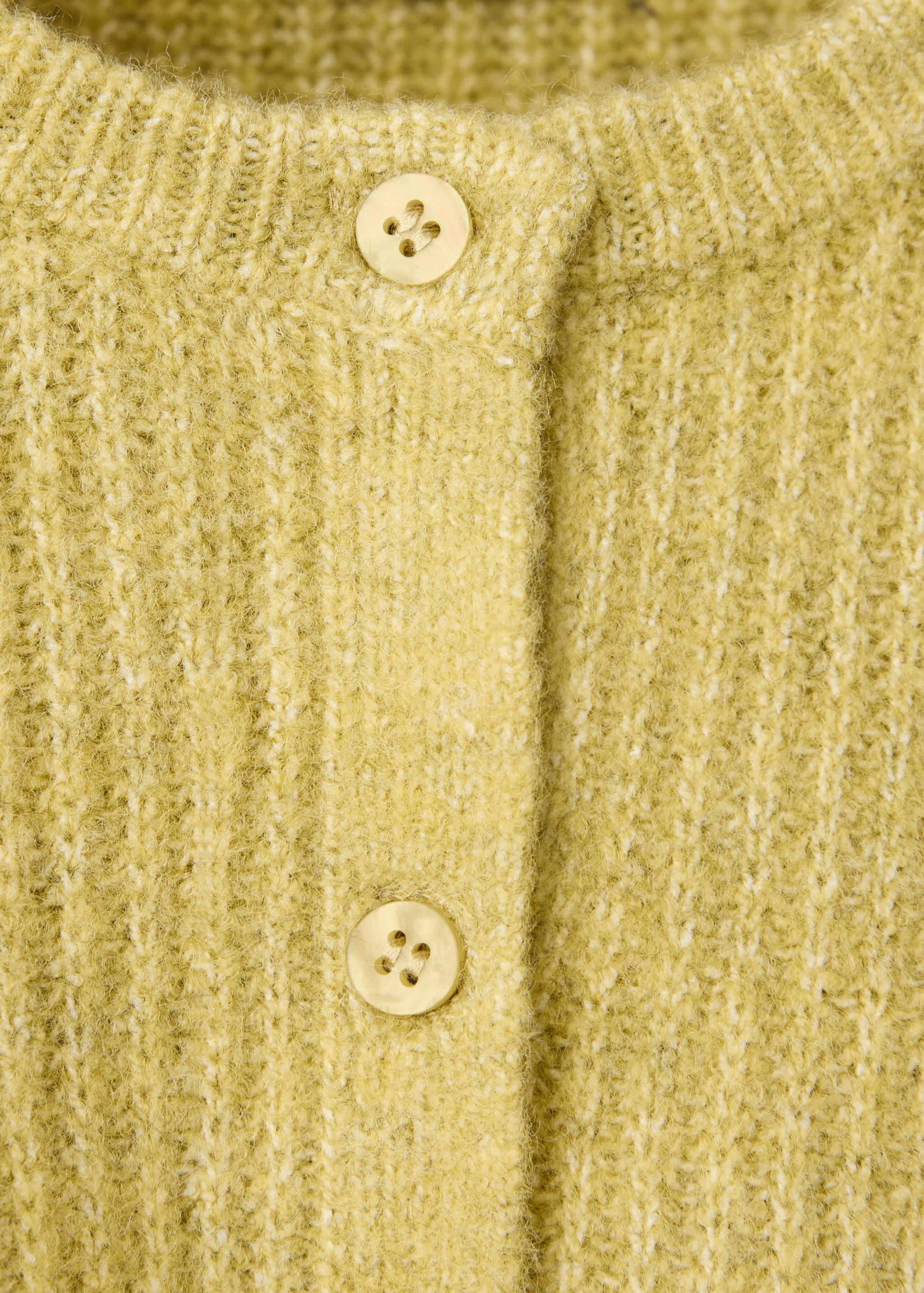 Close-up of a yellow-green knitted cardigan with button placket.