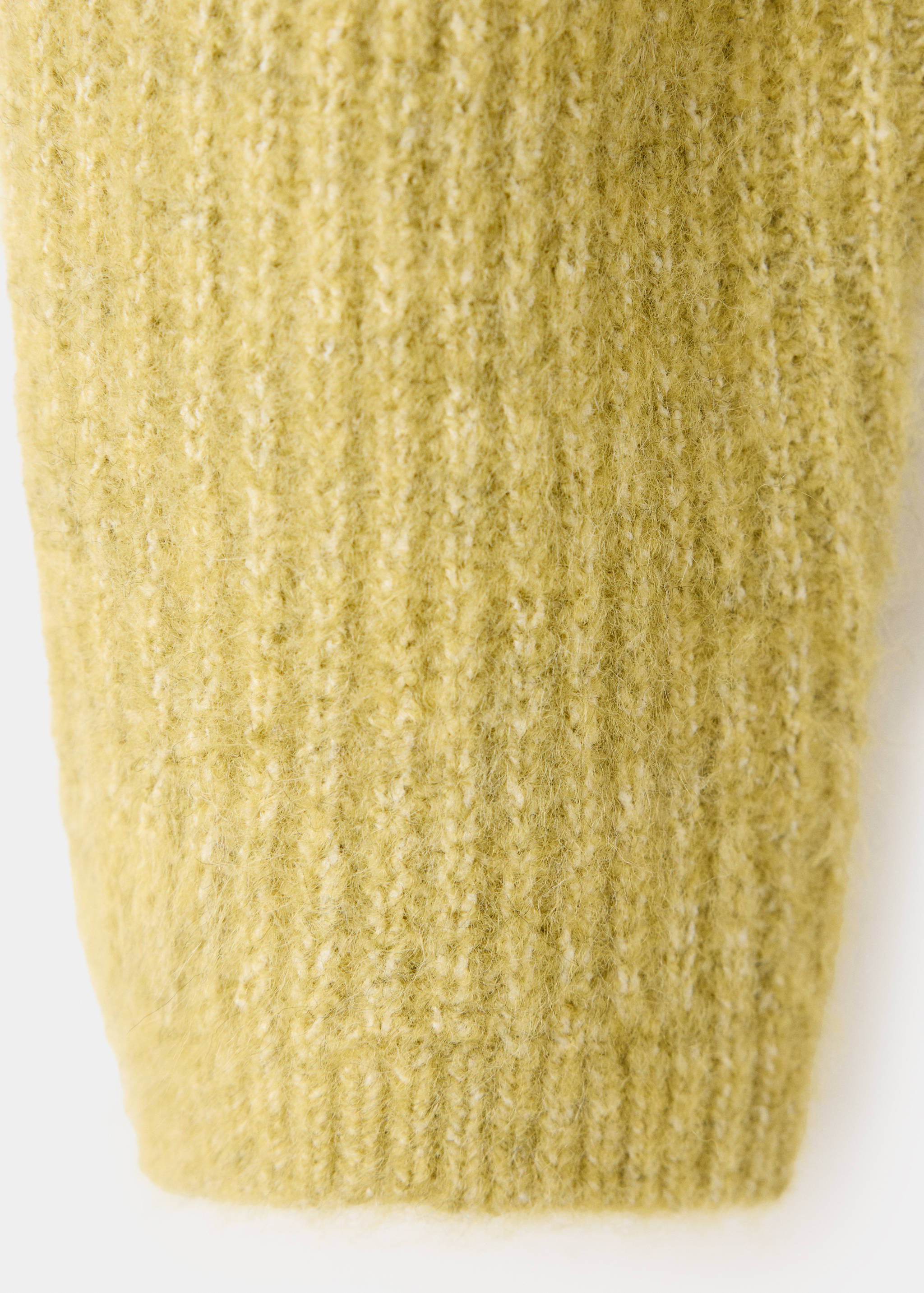 Close-up of the soft, fuzzy ribbed knit fabric of a yellow-green cardigan.