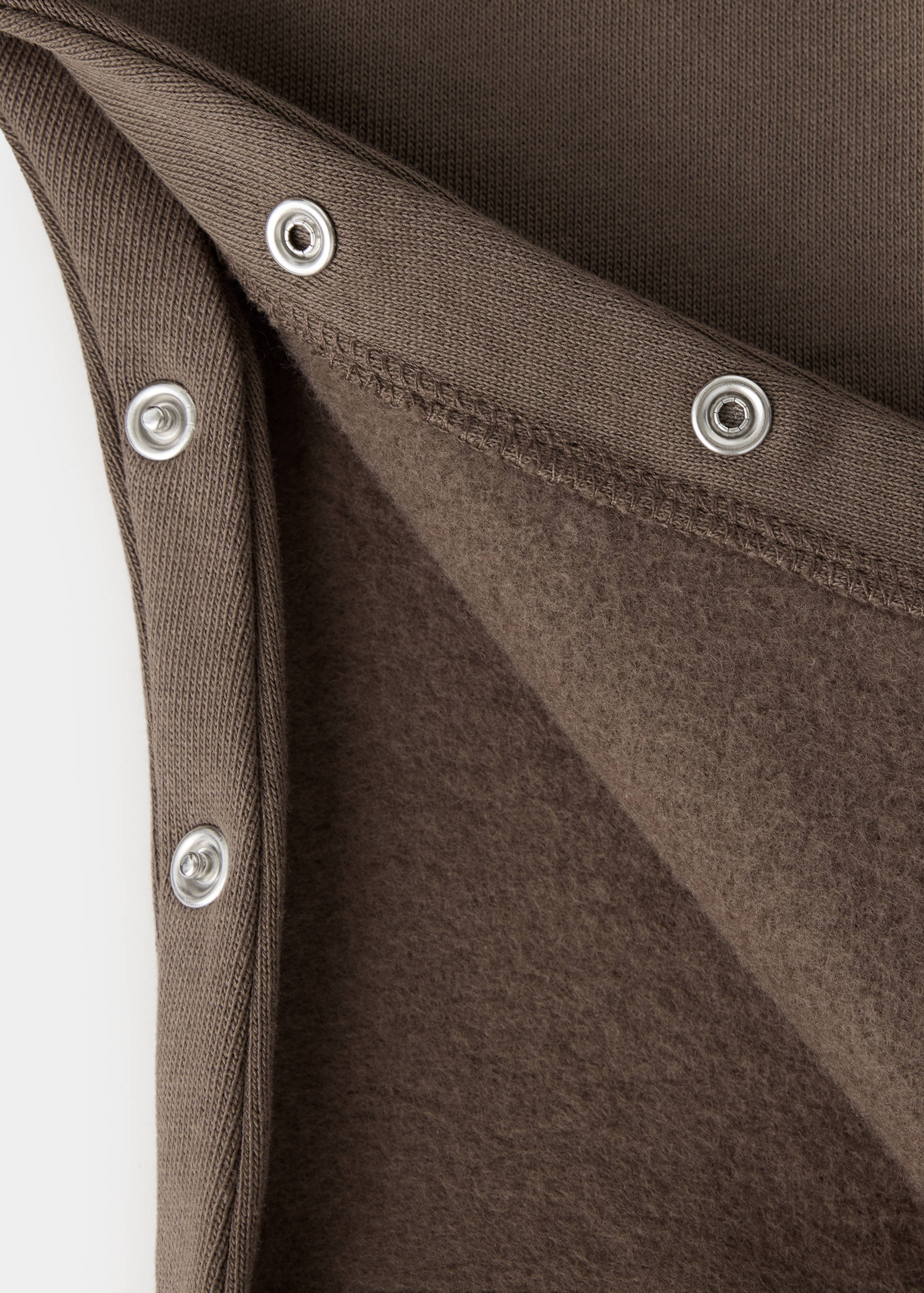 Brown children's dungaree fabric detail showing press-studs