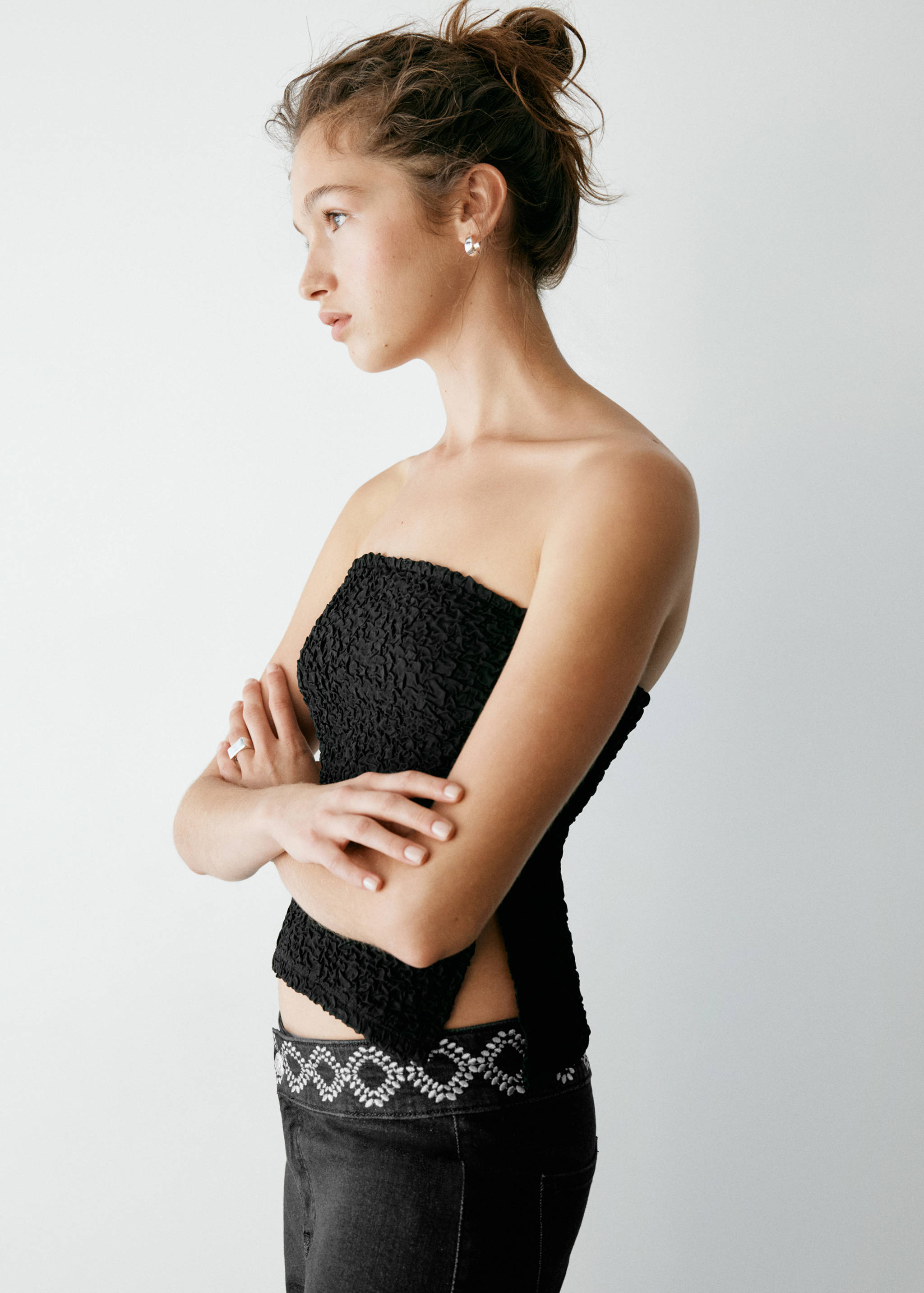 Black strapless textured smocked top paired with dark trousers.