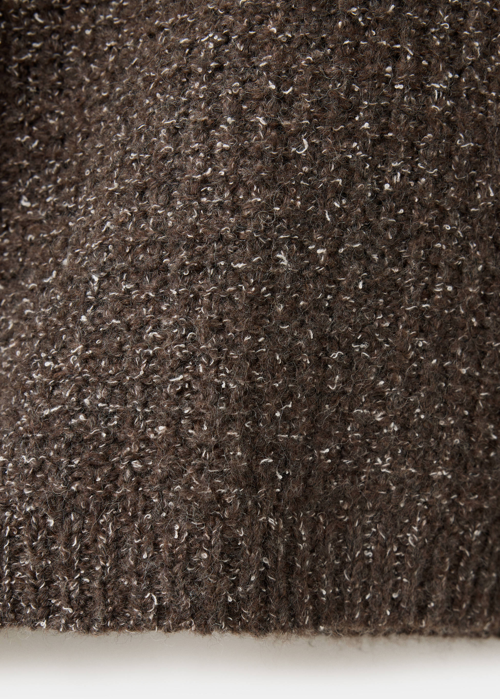 Close-up of the textured brown knit fabric of a sweater.