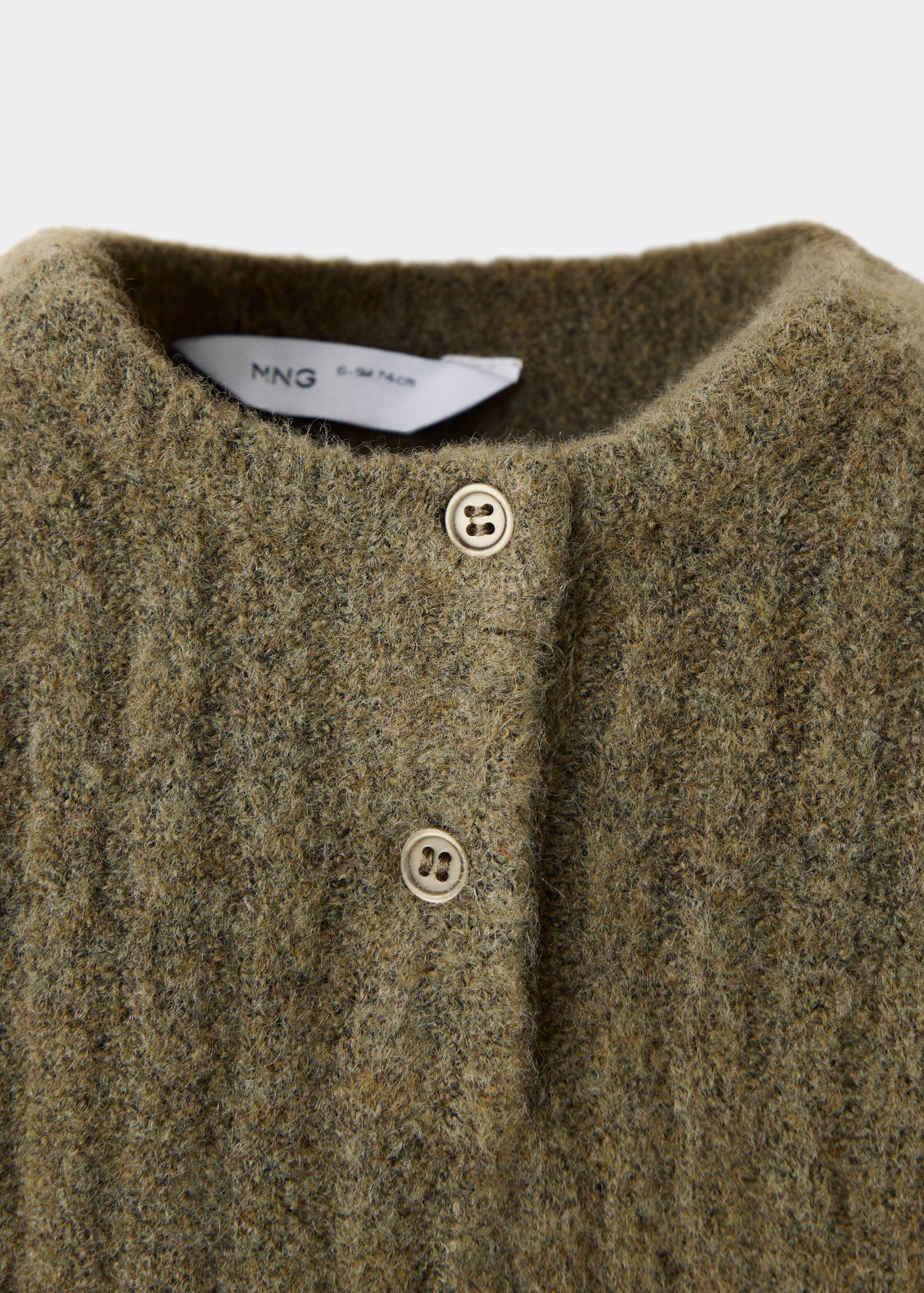 Close-up of a green knitted kids jersey featuring a button placket.