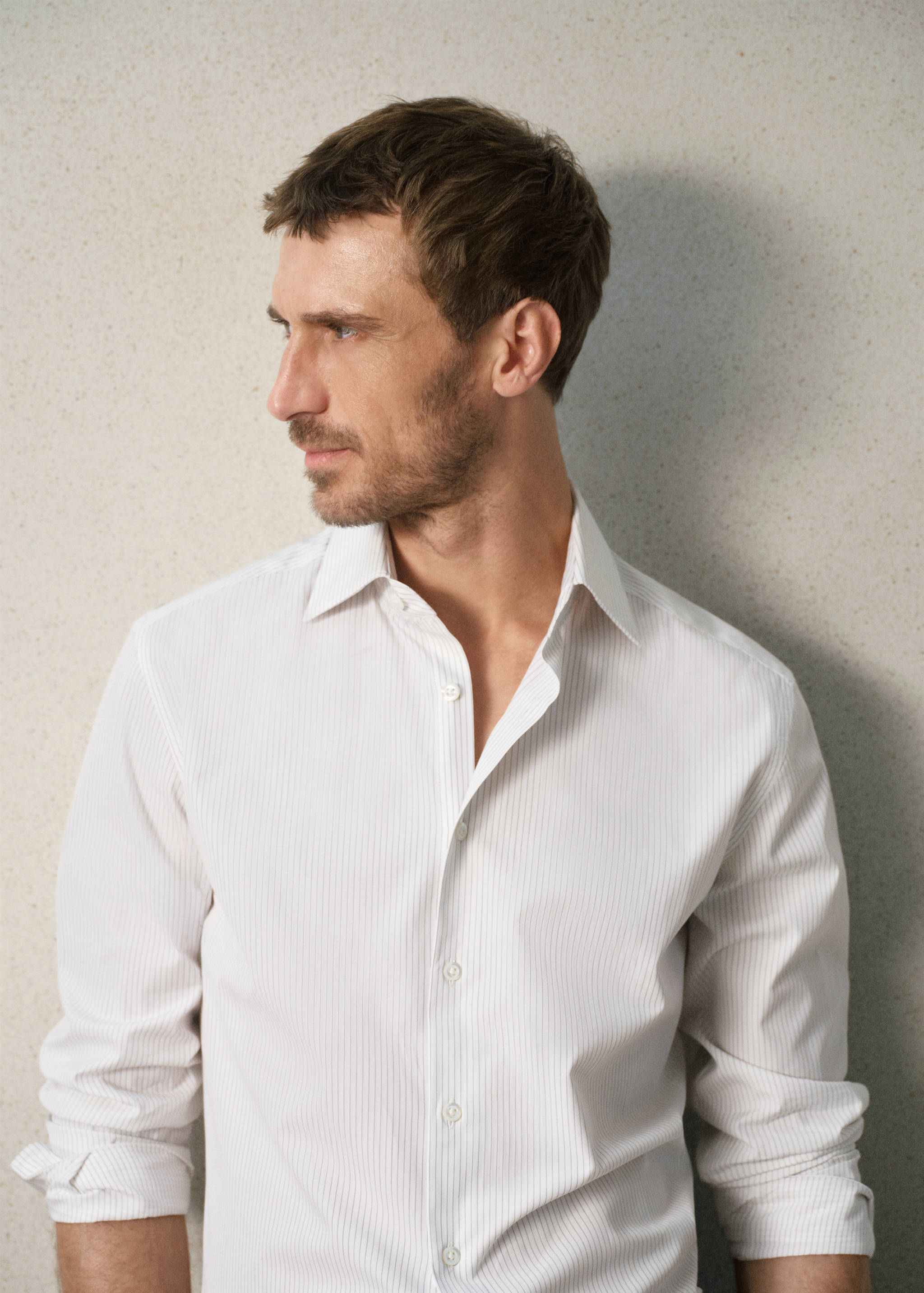 White striped shirt with a classic collar and long sleeves rolled up.