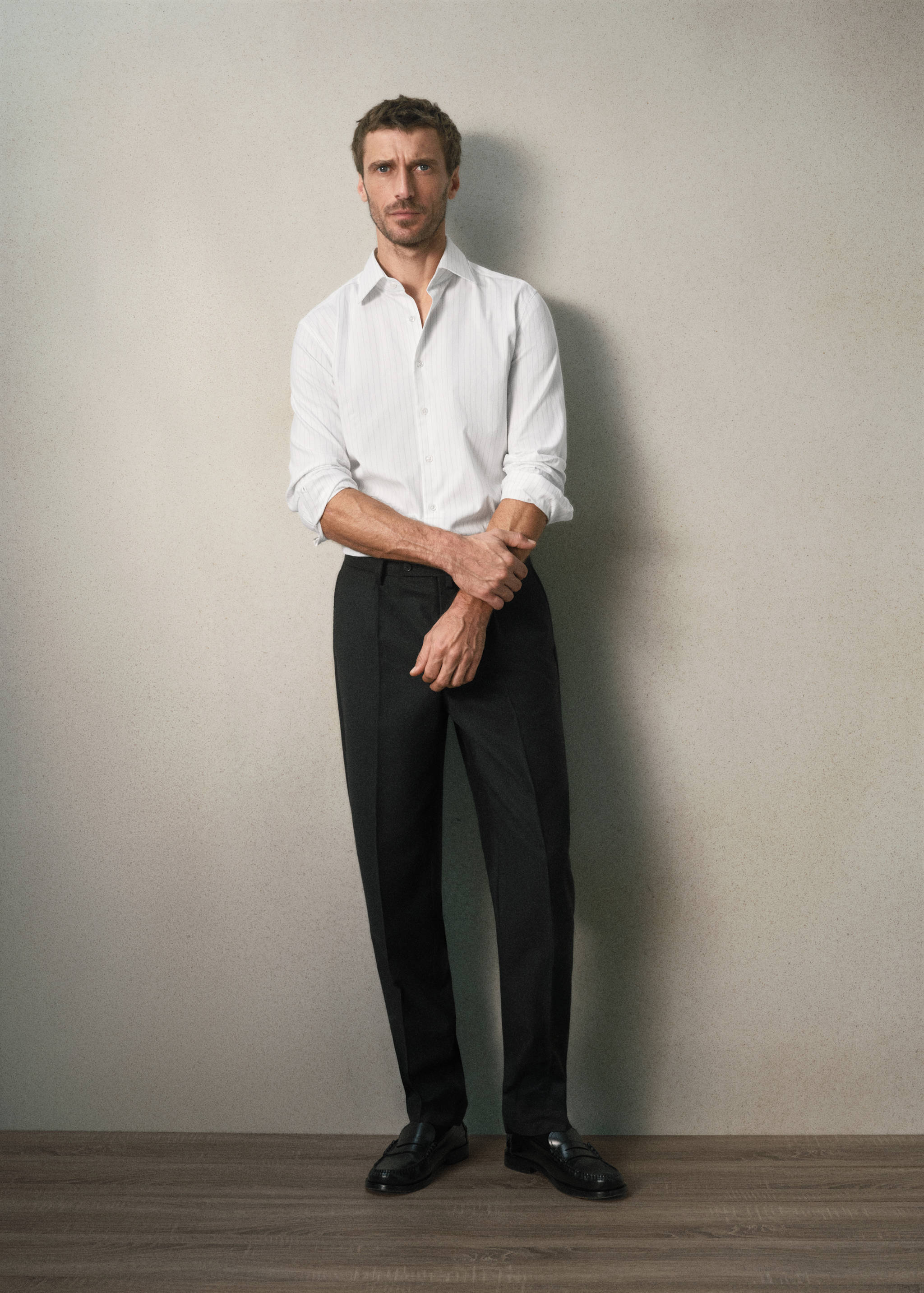 White long-sleeved pinstripe shirt worn with dark trousers.