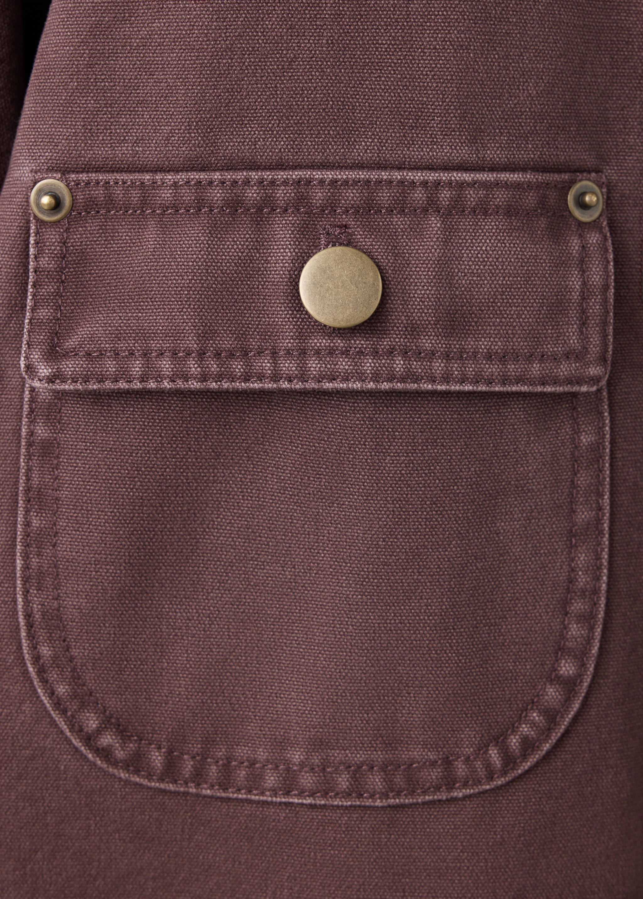 Close-up of the burgundy parka's fabric and riveted pocket.
